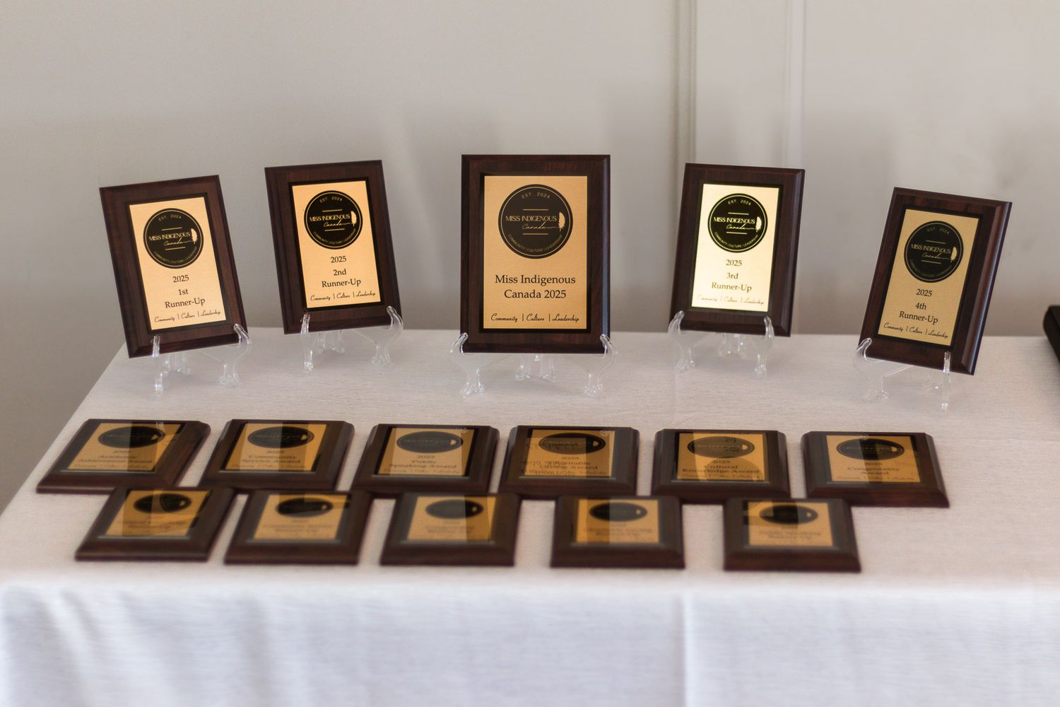 Row of wooden plaques or awards displayed on white table cloth.