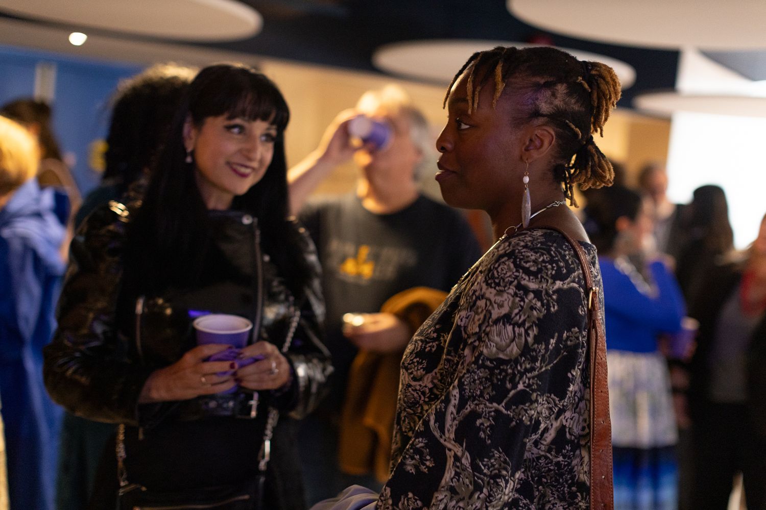 People engaged in conversation at an evening social gathering with modern lighting.