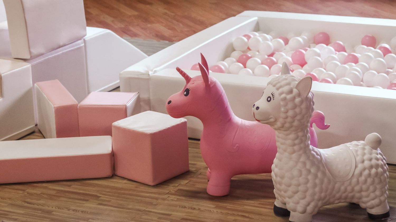 Pink and white decorative elements including stuffed animals arranged on wooden flooring.