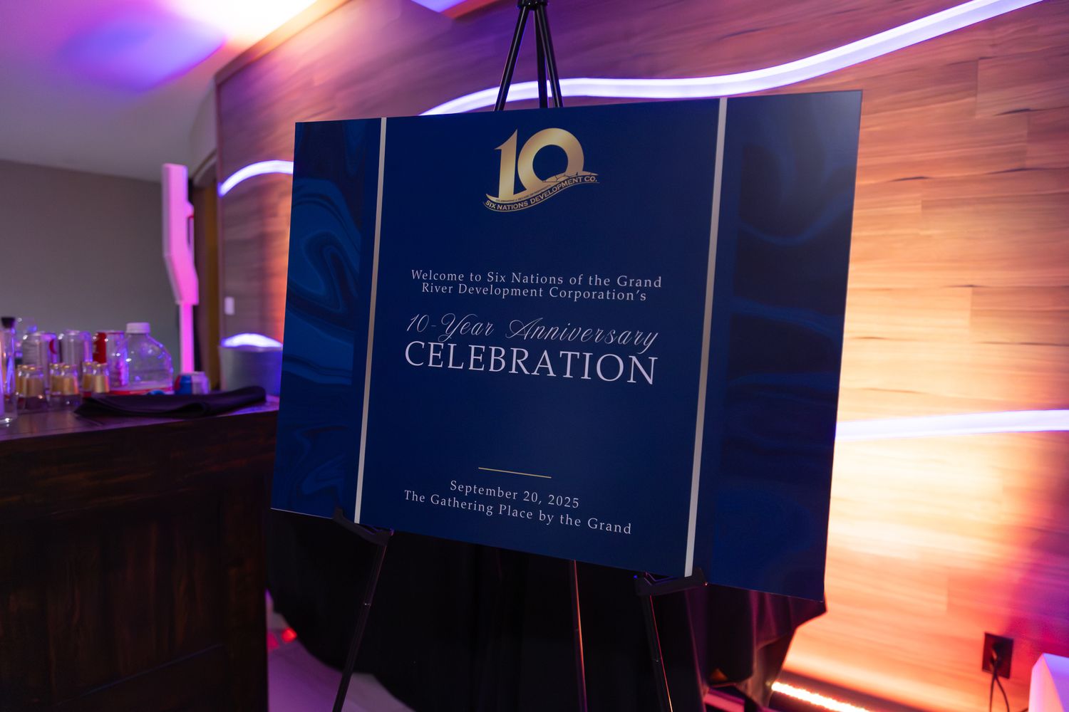 Corporate event signage and banners displayed against blue backdrop with lighting effects.