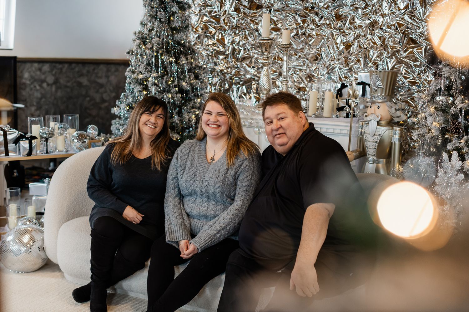 Family holiday photo session in front of a frosted Christmas tree with white and silver decorations.