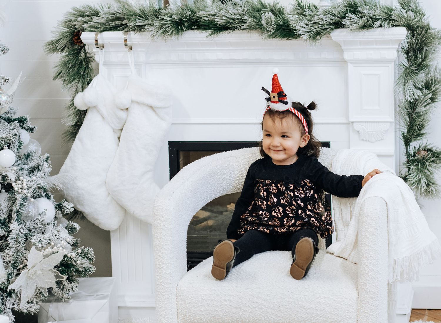Playful holiday photoshoot with flocked Christmas tree and white fireplace backdrop.