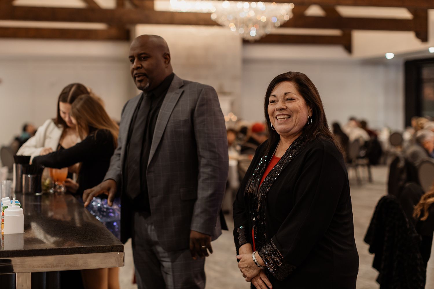 Attendees enjoying a formal event in an elegant banquet hall with exposed wooden beams and chandeliers.