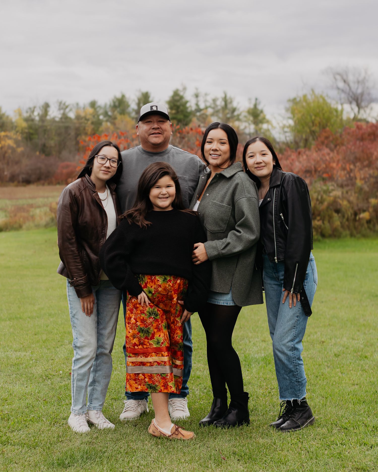 Casual outdoor group portrait with people gathered in front of fall foliage.