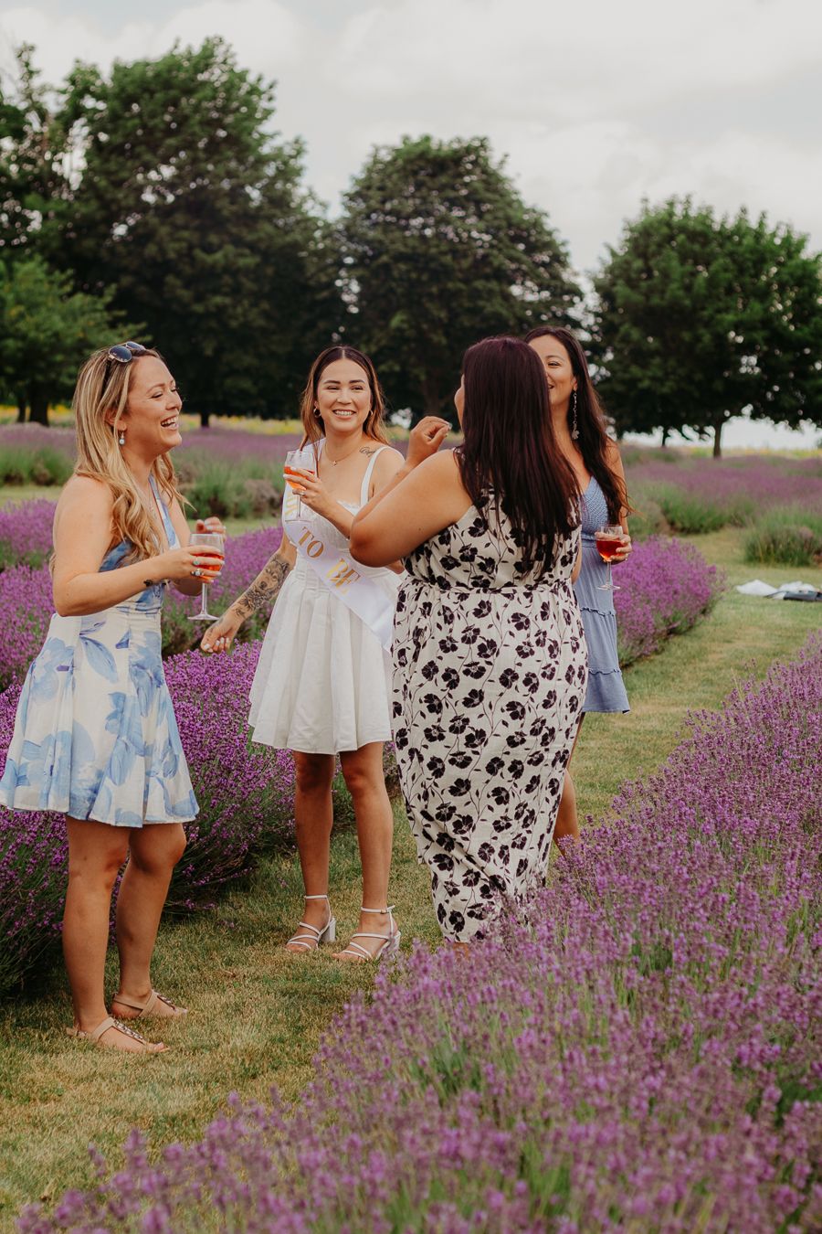 Friends celebrating in summer dresses among blooming lavender fields.