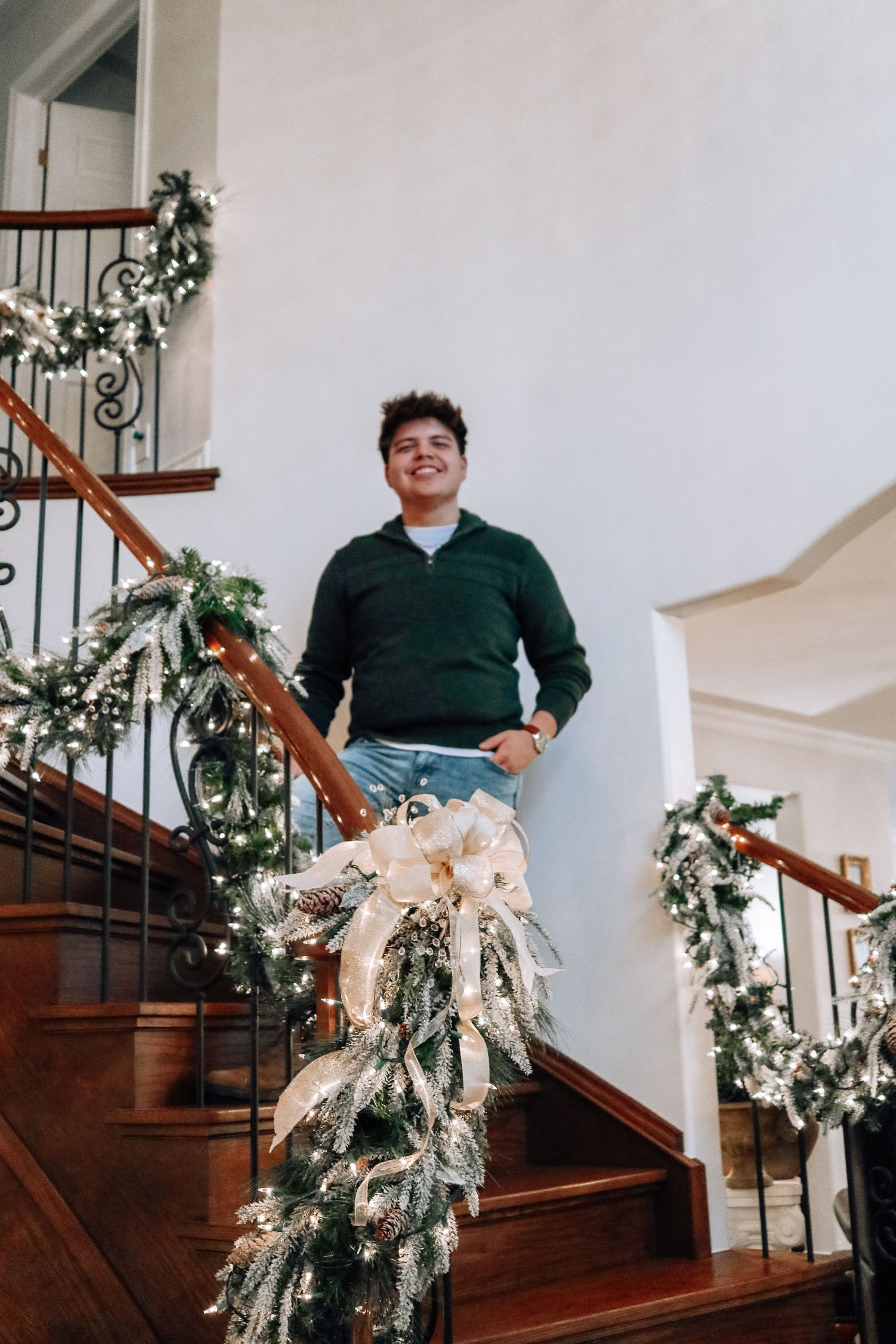 A staircase decorated with white and silver holiday garland and greenery for Christmas.