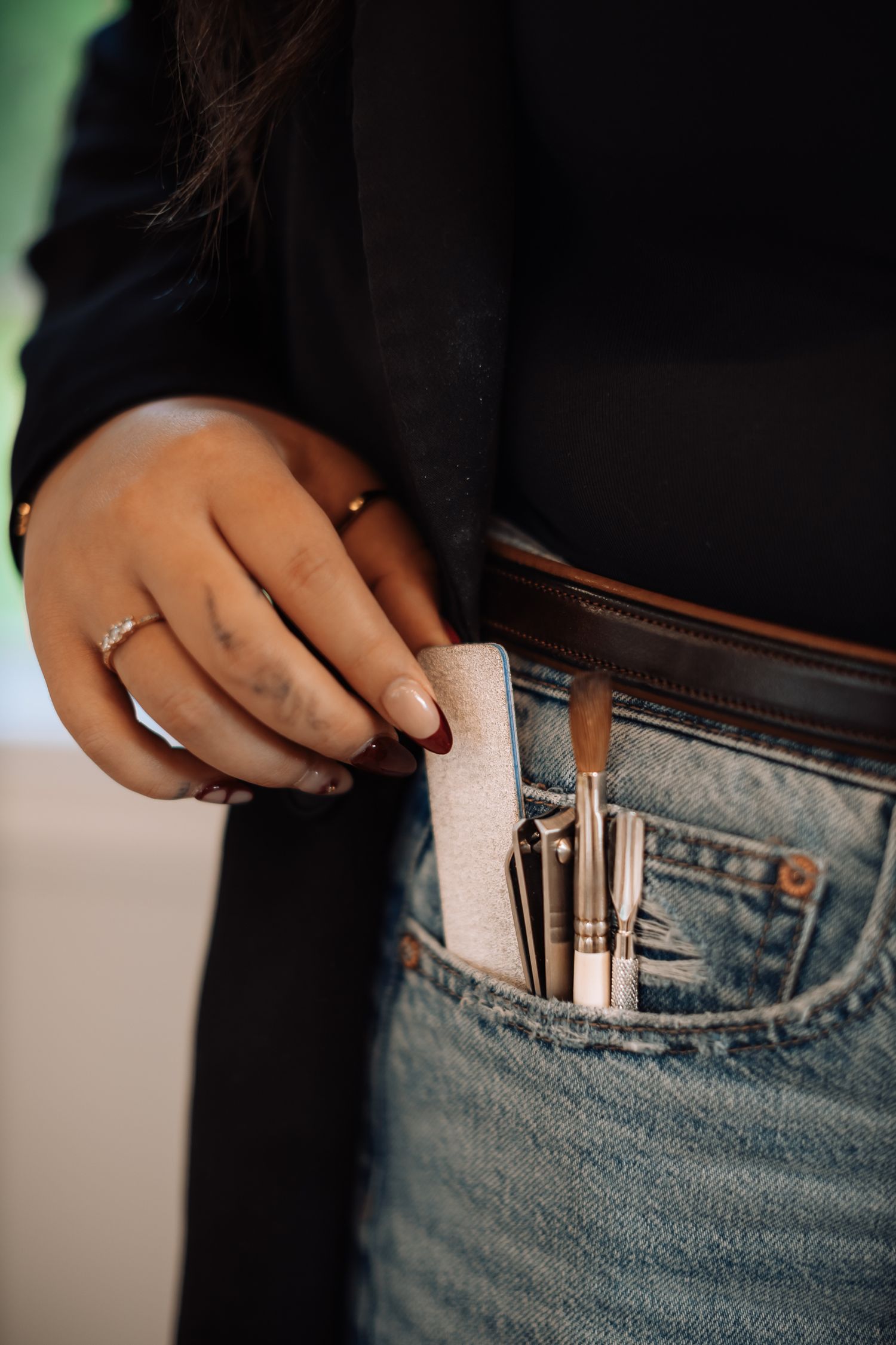 Close-up of nail polish bottles tucked into denim jeans pocket.