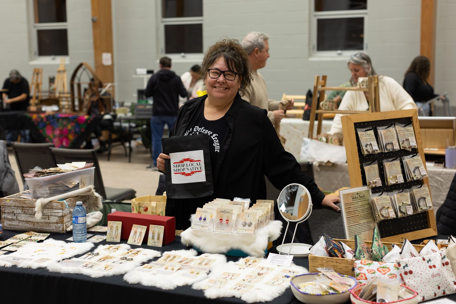 Vendor tables lined up at an indoor craft fair with handmade items for sale.