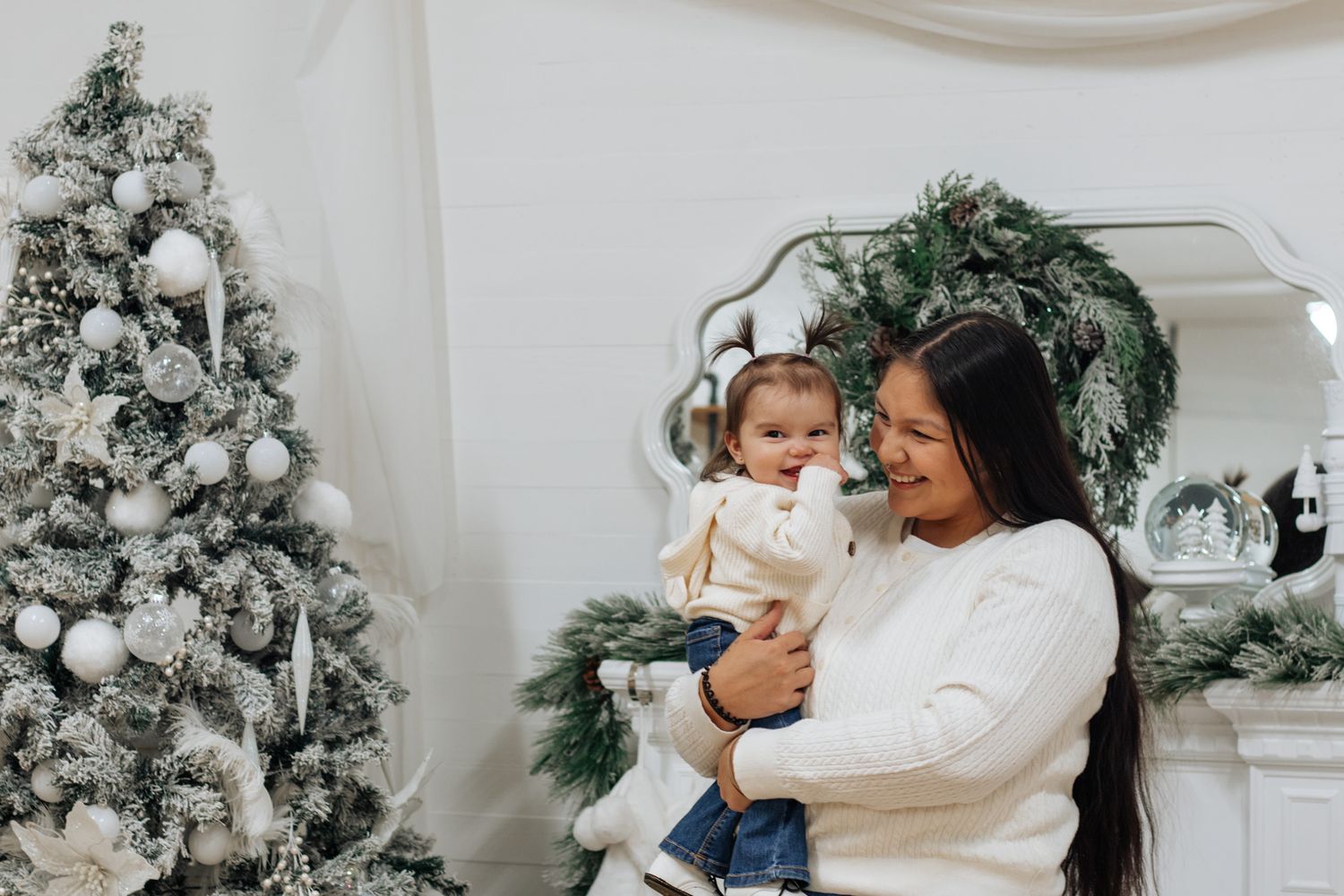 Intimate family moment captured during Christmas photo shoot with white decorated trees.