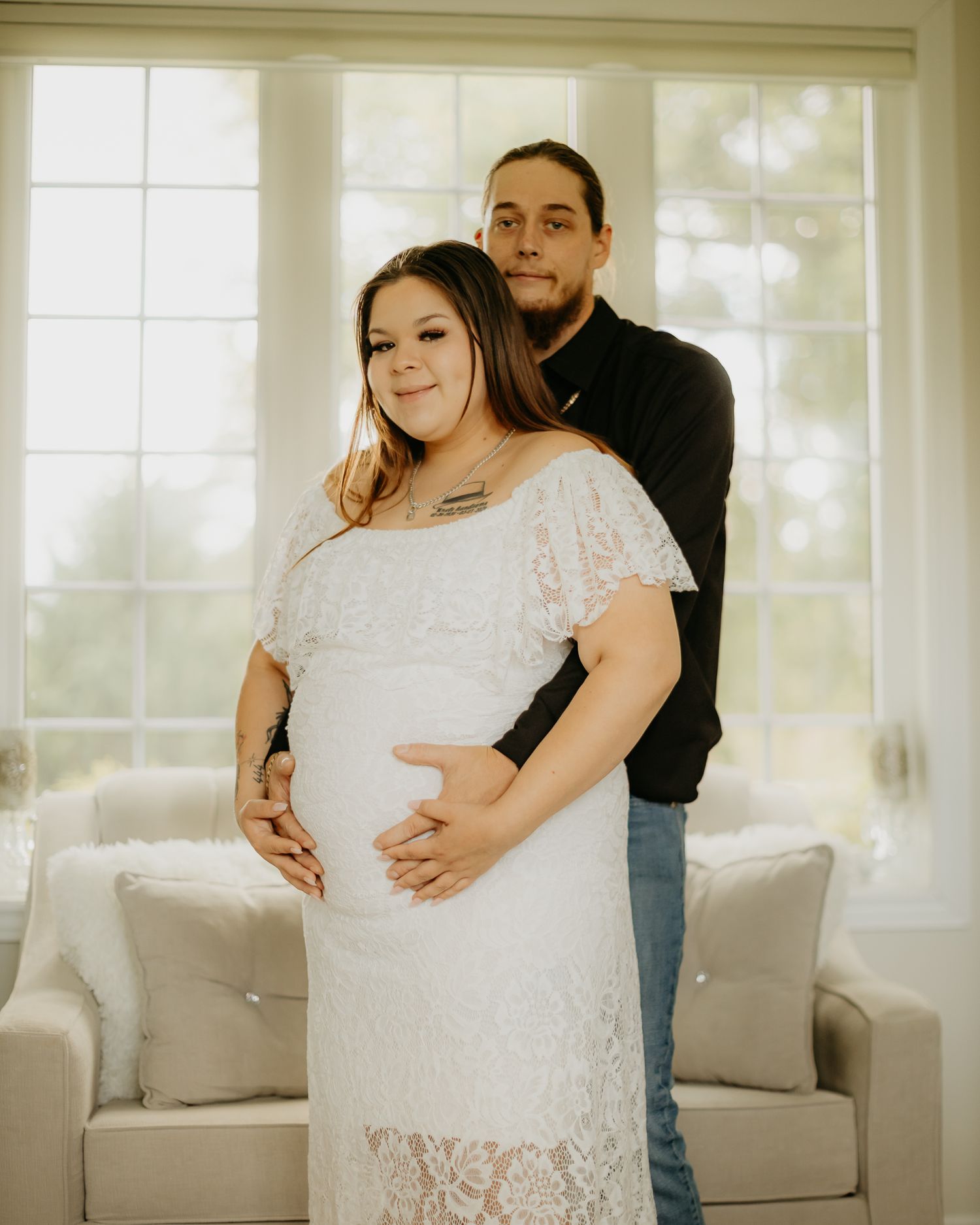 Couple shares intimate moment in bright indoor setting with white furniture.