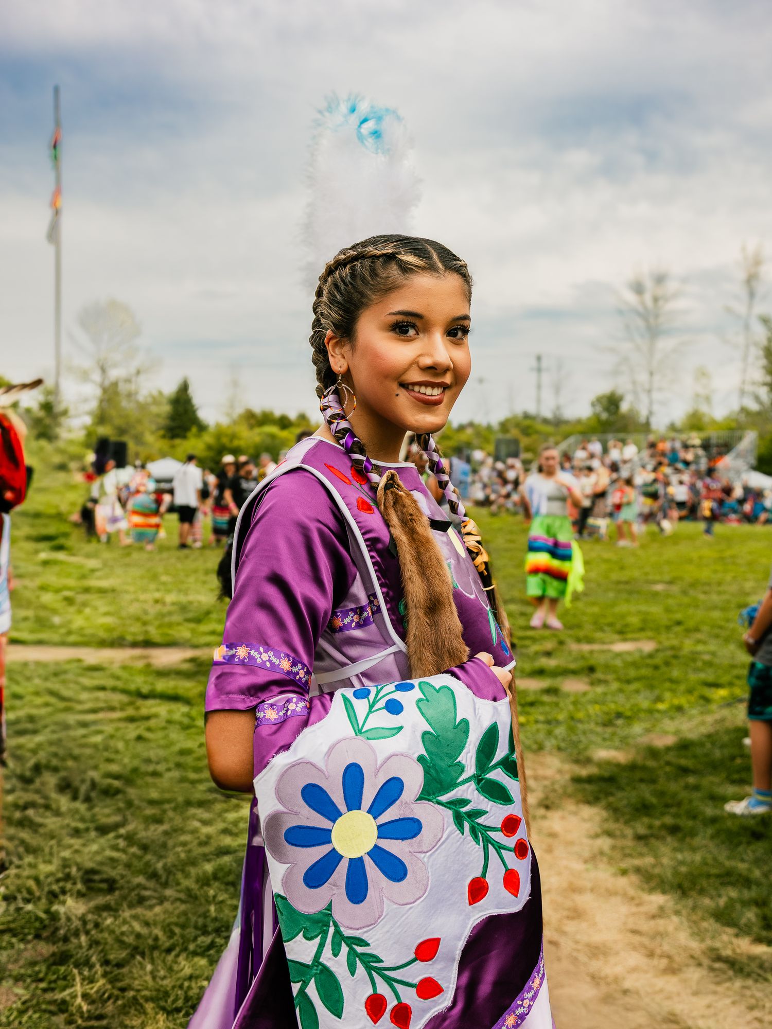 Traditional purple regalia with colorful floral designs displayed at an outdoor cultural event.