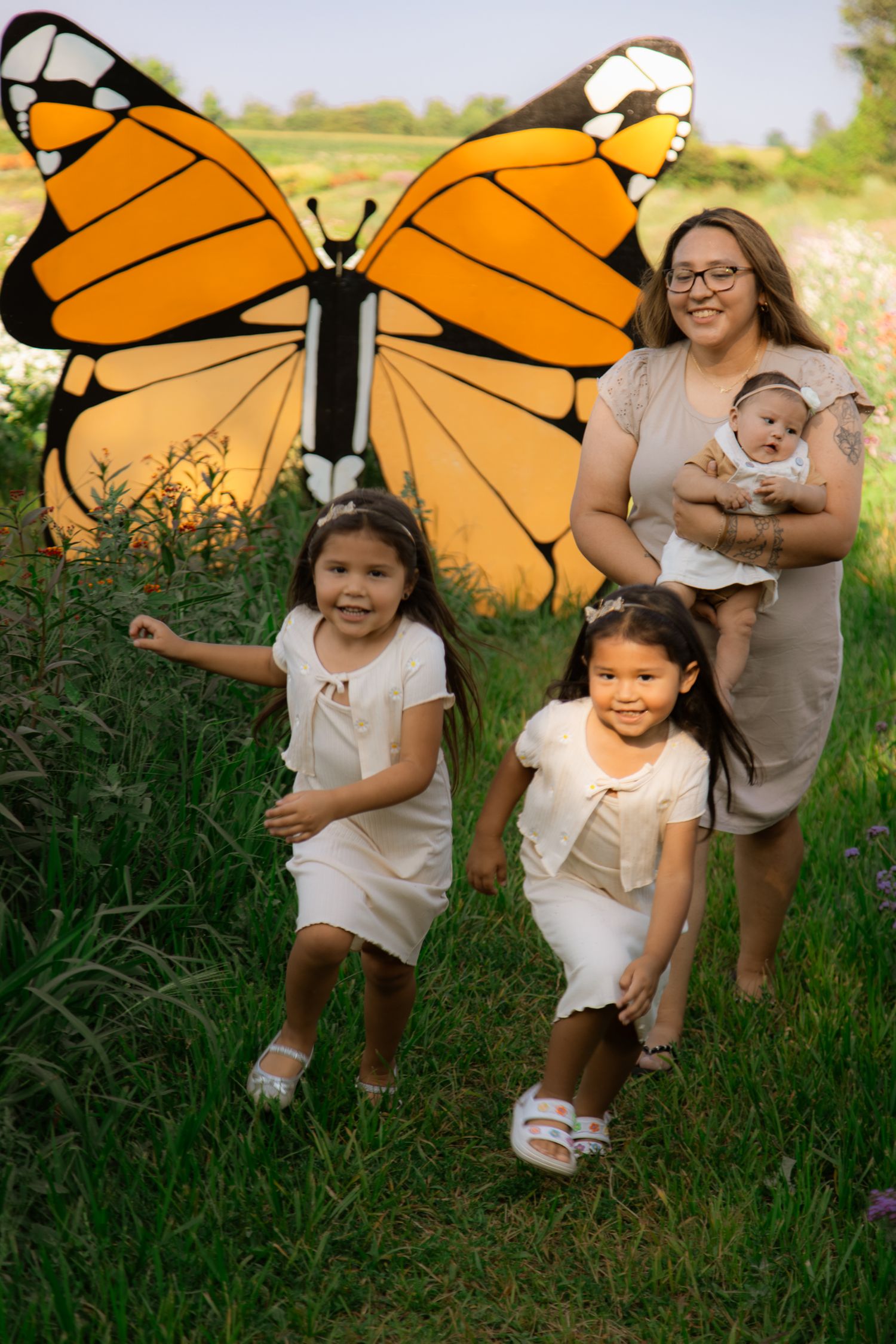 Large orange butterfly wings frame a playful outdoor photoshoot in tall grass.