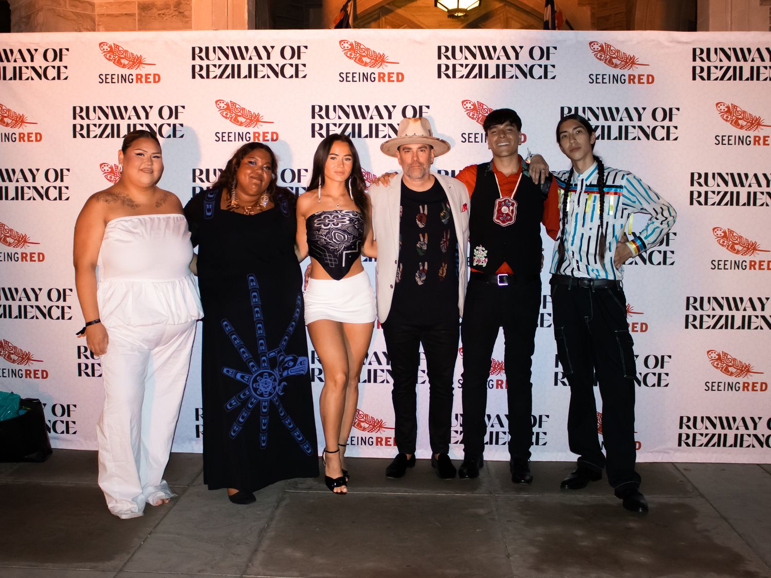 Six people posing together in front of a Runway of Rezilience step-and-repeat backdrop.