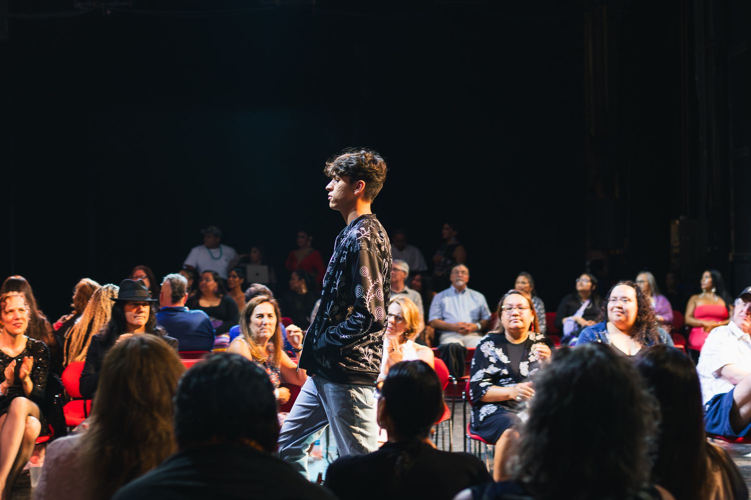 Audience members watching and cheering at a performance event.