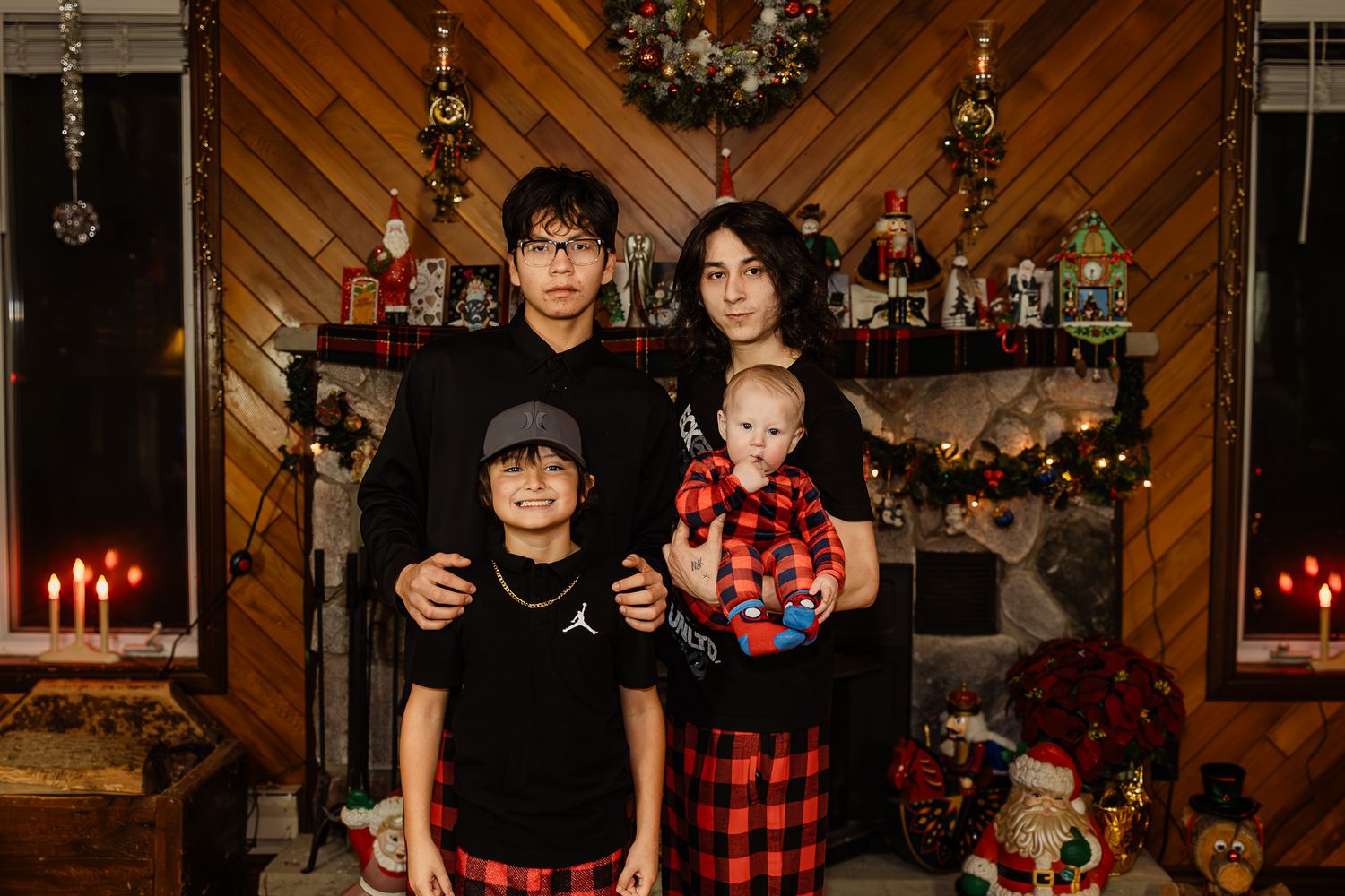 Holiday gathering in front of decorated Christmas tree with wood paneled walls and candles.