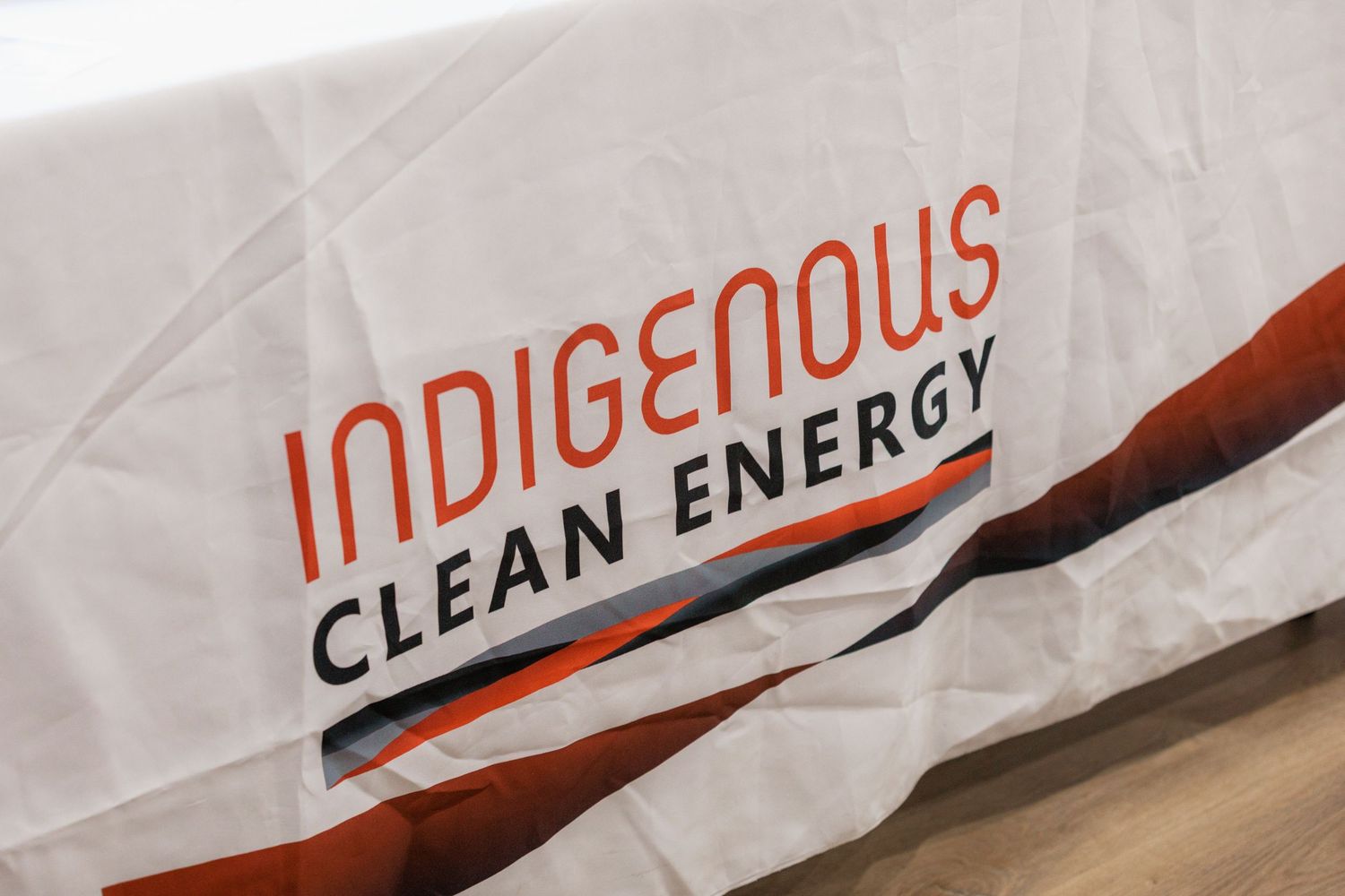 White tablecloth banner displaying the Indigenous Clean Energy logo in bold orange and black text.