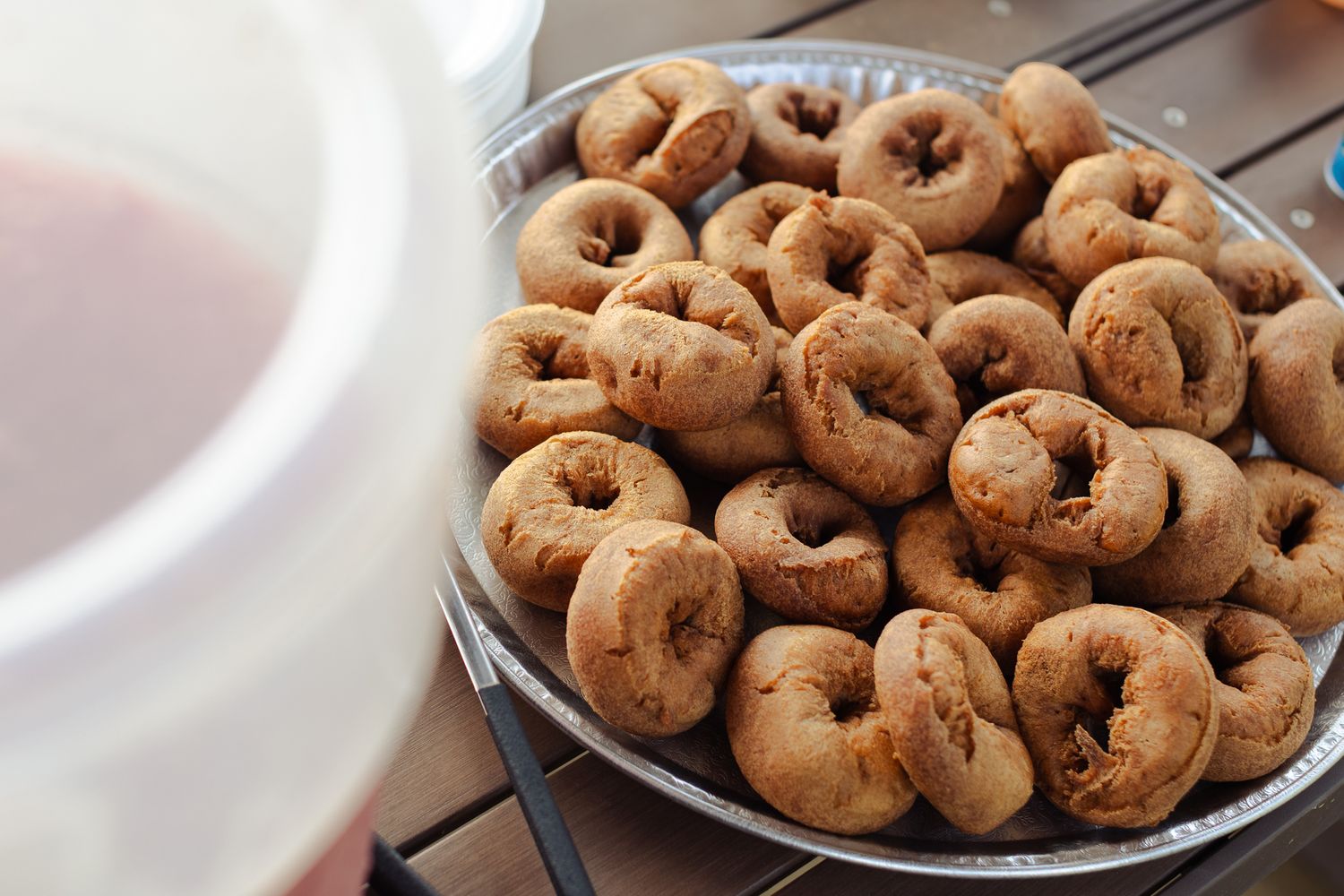 A plate of freshly baked mini donuts piled high on a metal tray, perfect for a sweet snack or dessert.