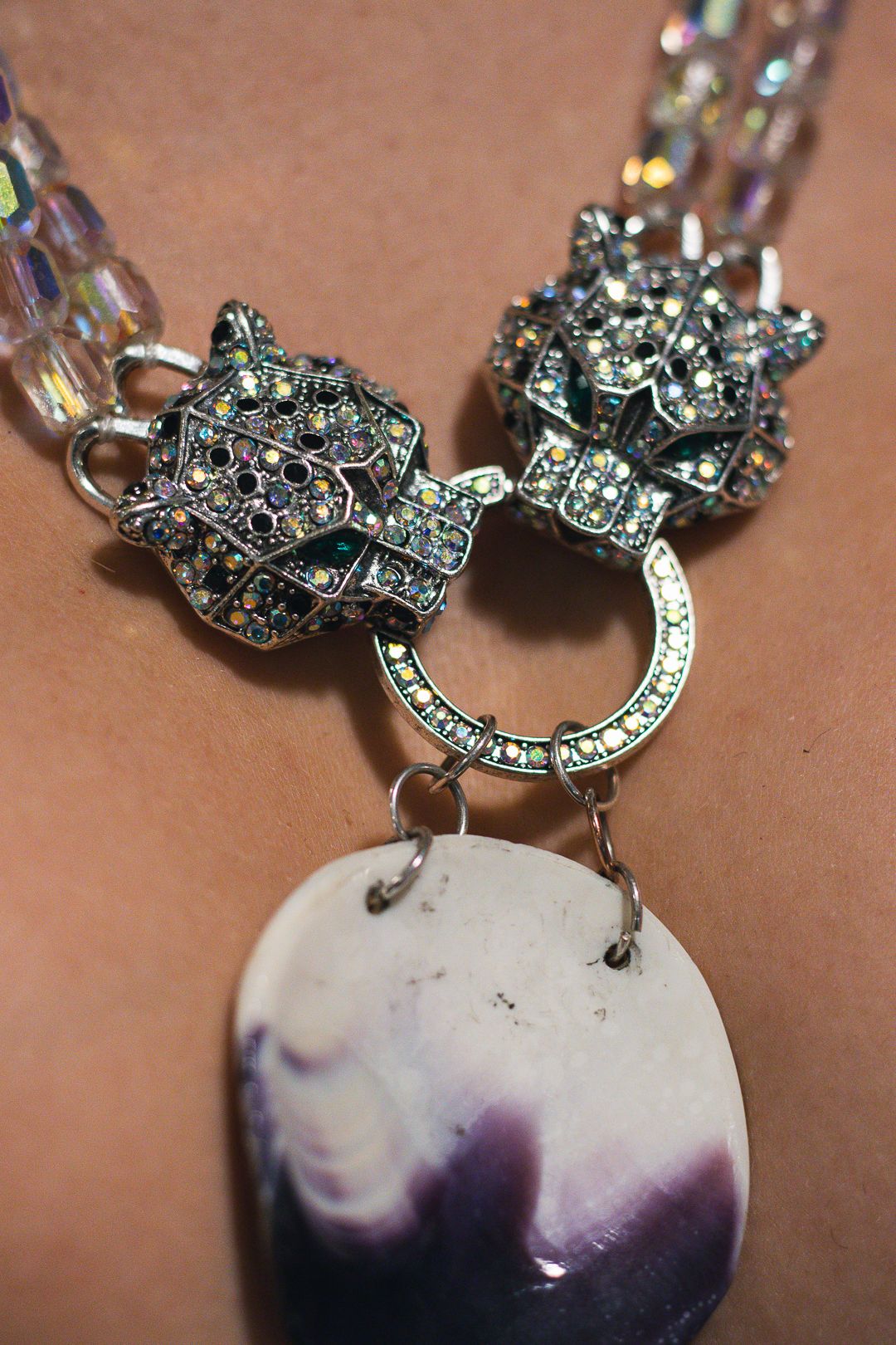 Ornate crystal necklace with gemstone pendant and rhinestone clasps closeup.