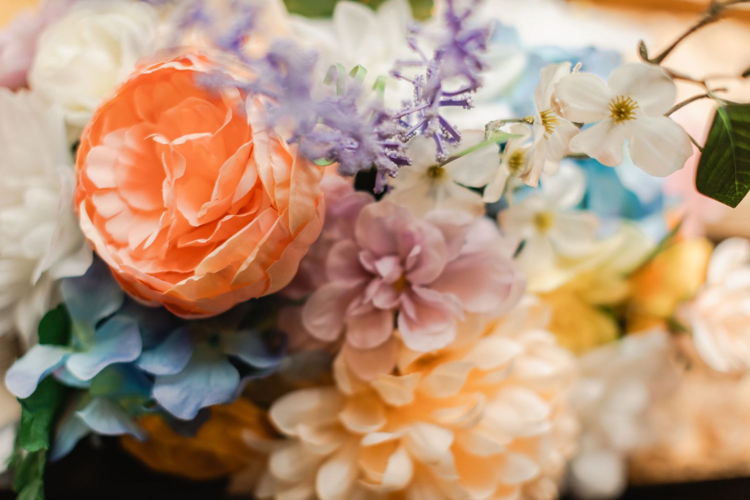 Colorful arrangement of pastel artificial flowers including peach rose, lavender blooms, and white blossoms.