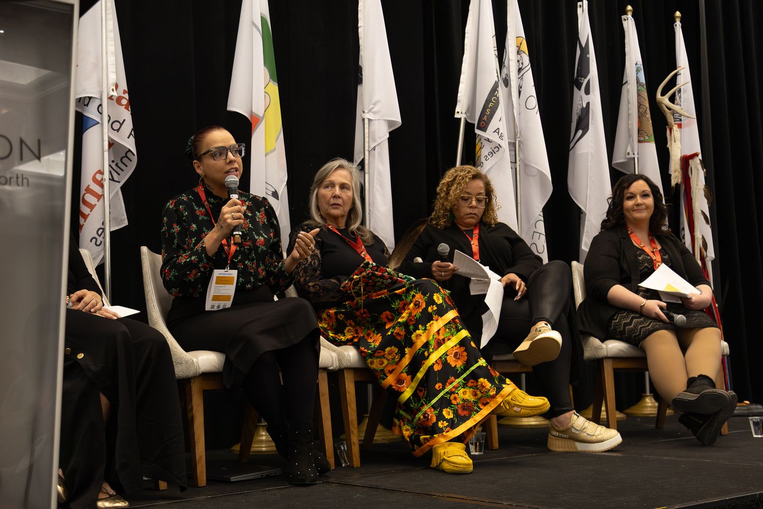 White banners displayed against dark backdrop with seated attendees in foreground.
