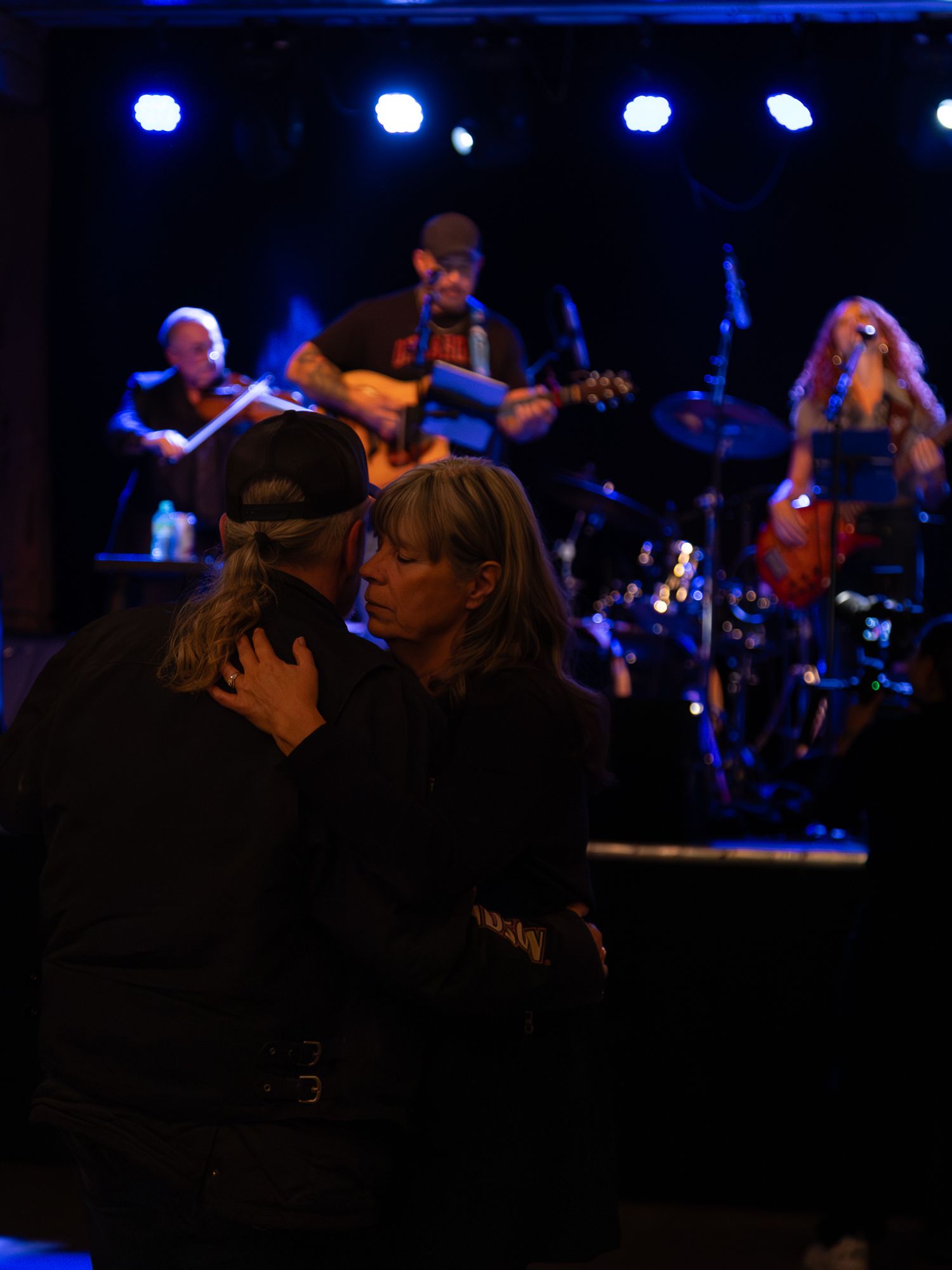Couples dance while a band performs on stage in the background.
