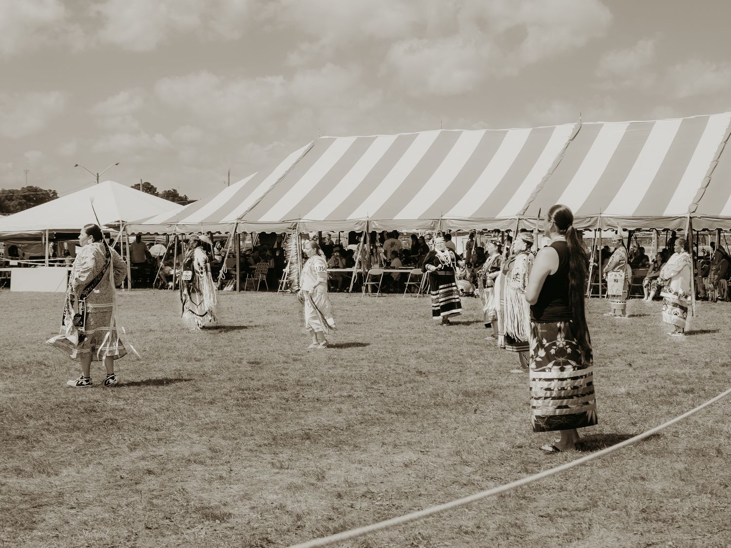 Aerial view of white tents and festival grounds at a Native American powwow gathering.