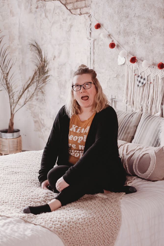 Lifestyle boudoir photography session on white bedding with boho decor elements.