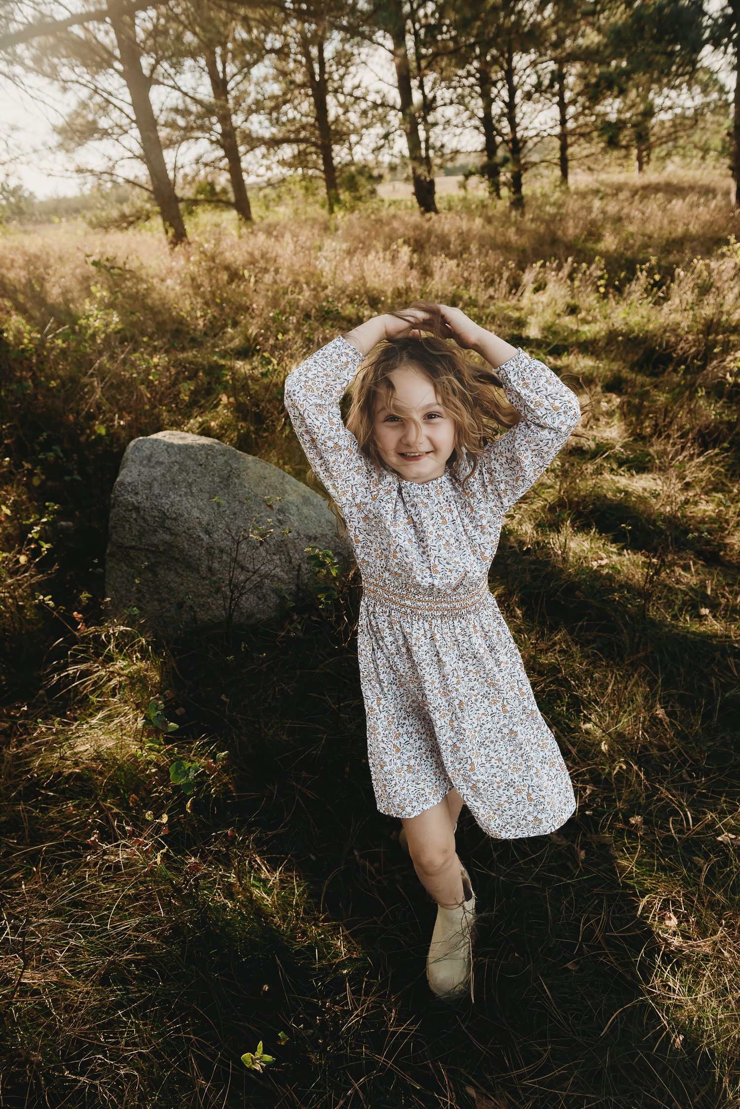A playful scene in golden sunlight with someone laying on a rock in a polka dot shirt.
