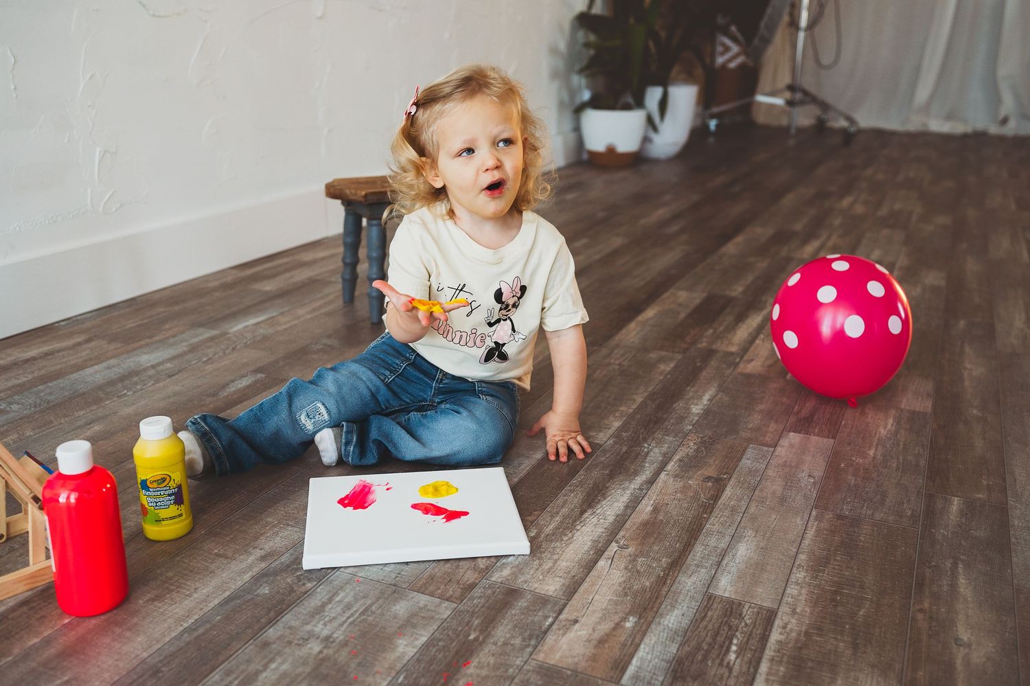 Child playing with red and white toys on hardwood floor.