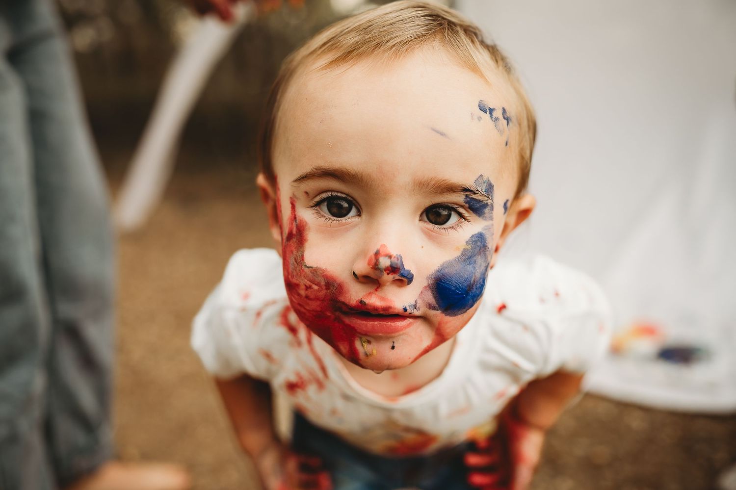 Paint-covered smiles during a messy art session outdoors.