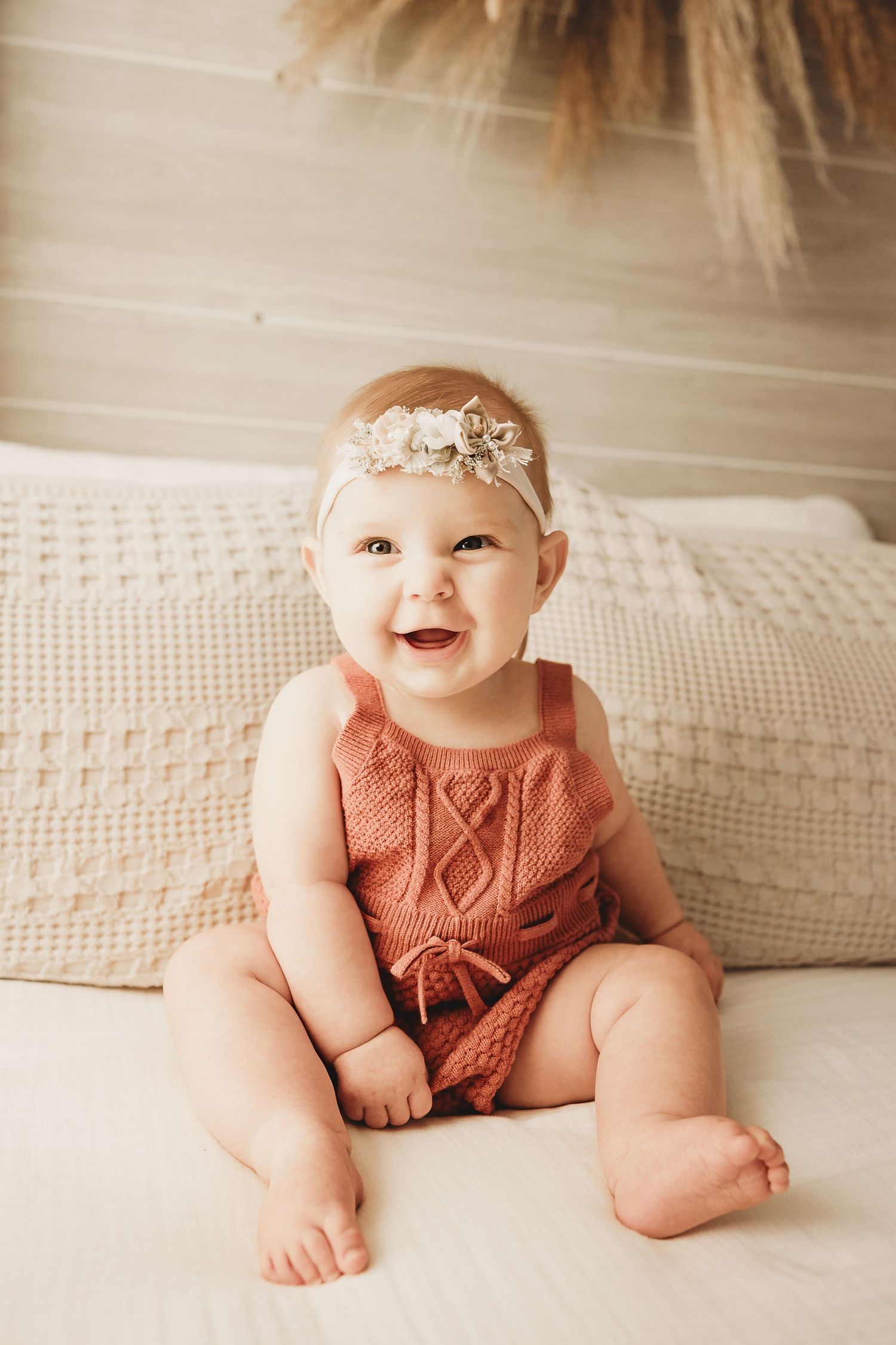A sweet little one shows off her leg rolls and smiles during a milestone session for the baby's first year membership at the studio