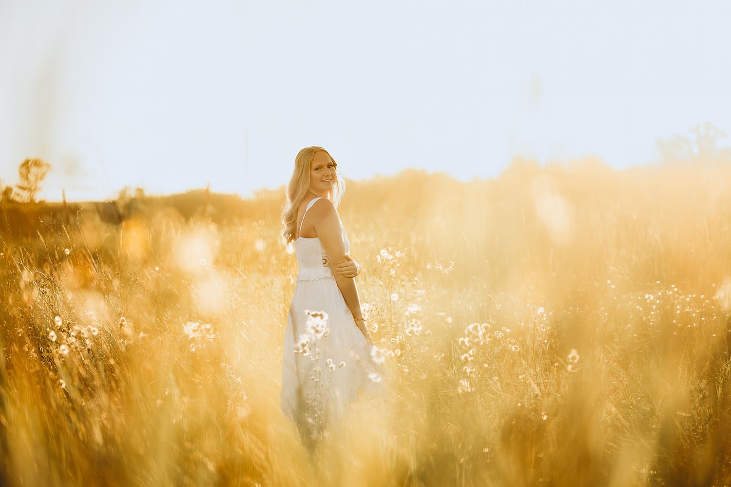 Ethereal golden hour photography in tall grass field with sun flare effects.