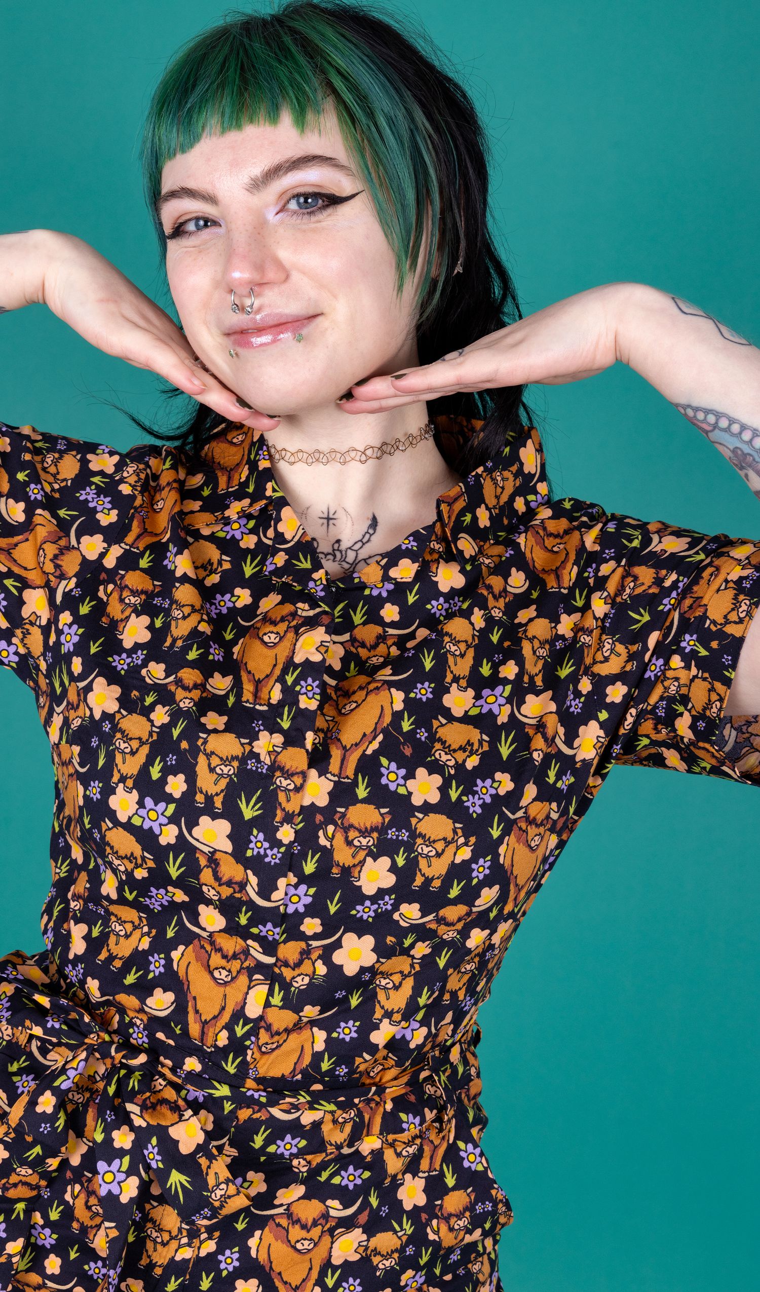 Faeryn a non binary femme person smiling at camera wearing a cow print jumpsuit by Run & Fly