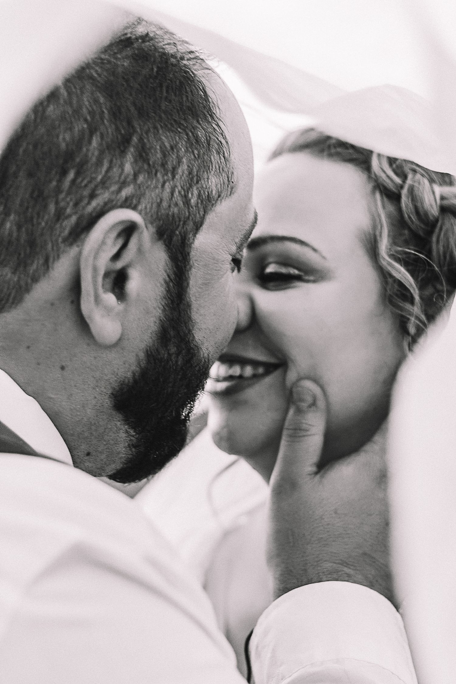 Emotional black and white wedding portrait of a bride and groom sharing a close laugh.
