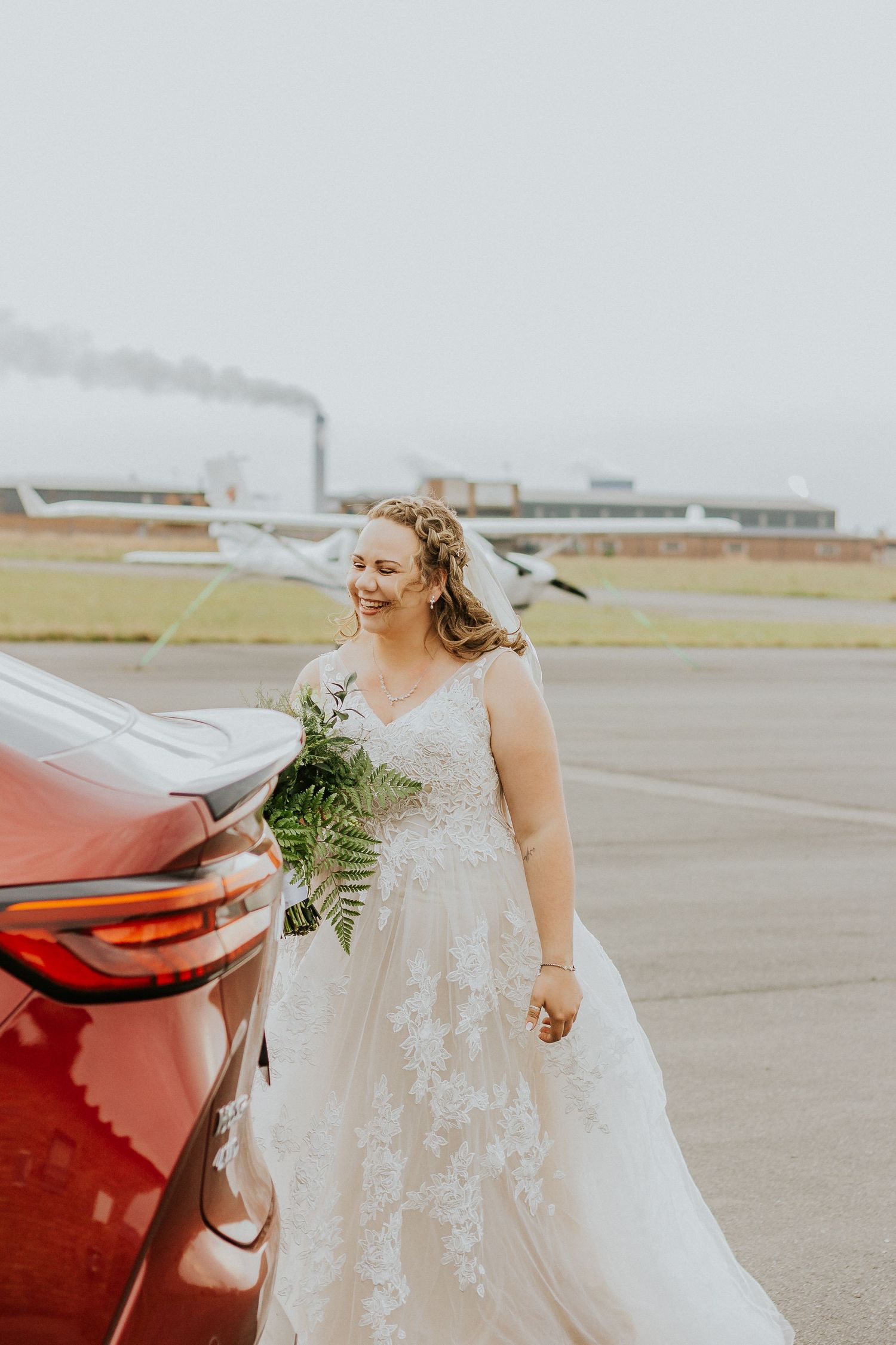 Creative wedding photography featuring a bride posing next to a classic red vehicle.
