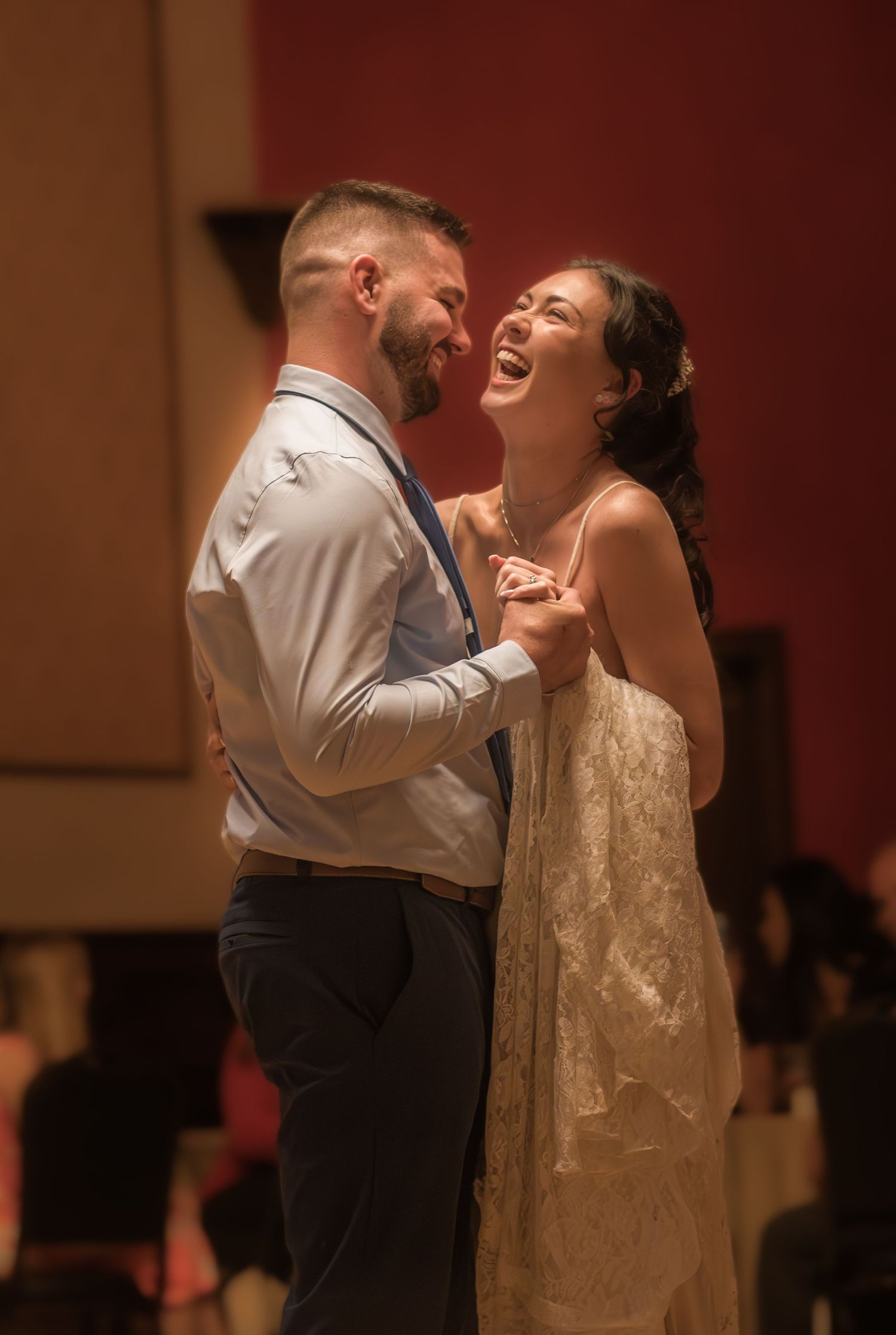 Couple shares intimate dance moment under warm lighting at reception.
