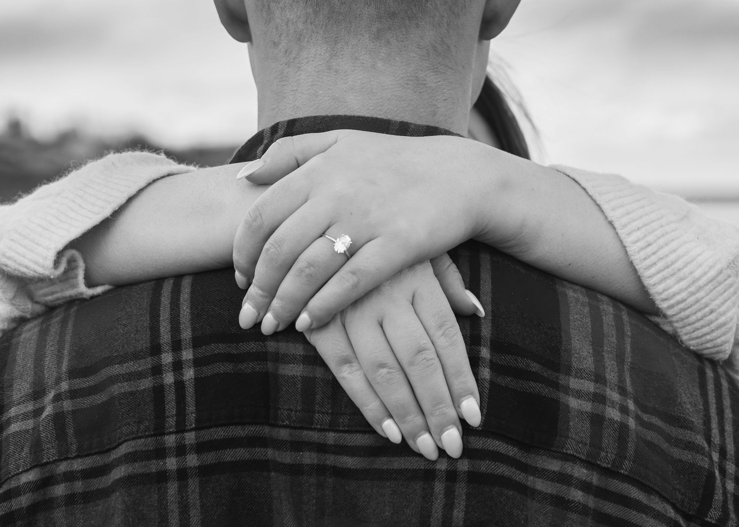 Close up black and white shot of hands resting on plaid fabric.