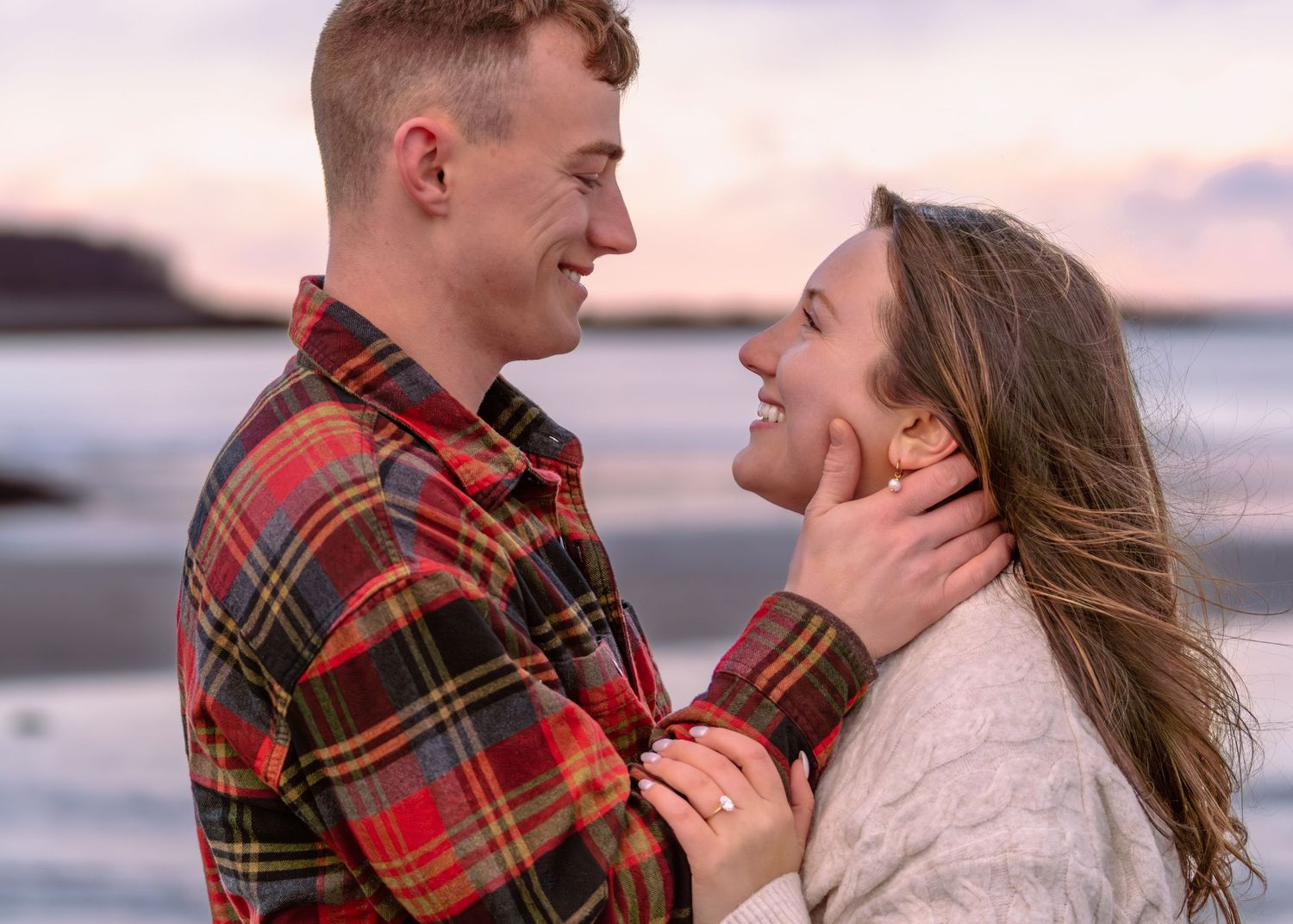A couple shares joyful laughter and embraces during a sunset beach photoshoot.