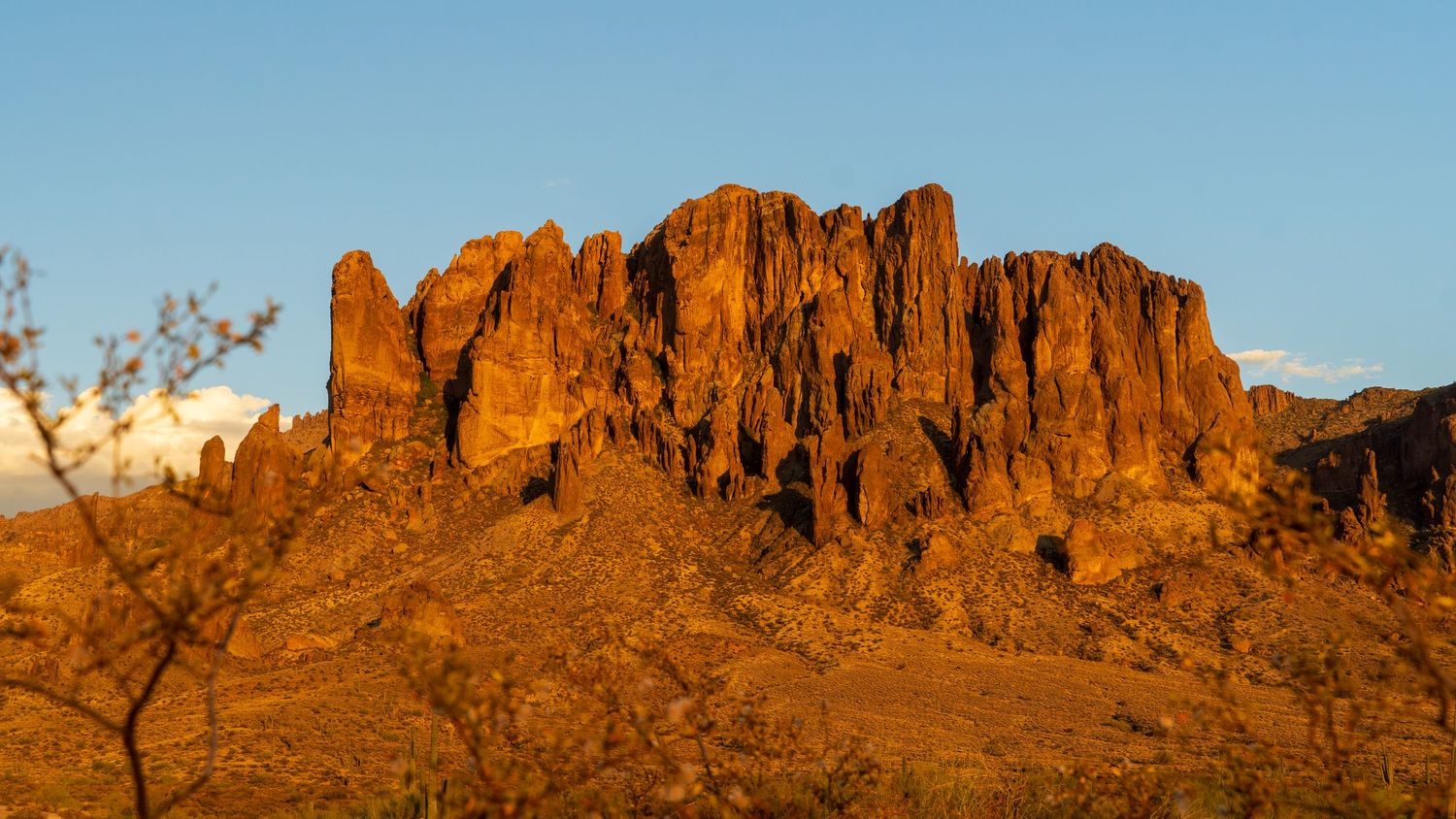 Panoramic view of rugged desert mountain peaks silhouetted against clear blue sky.