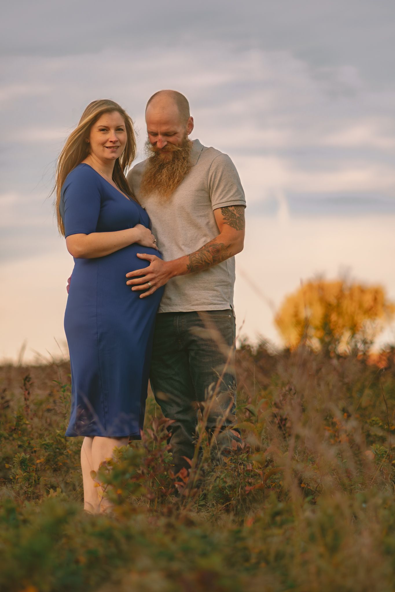 Expecting couple shares tender moment in wildflower field during golden hour.