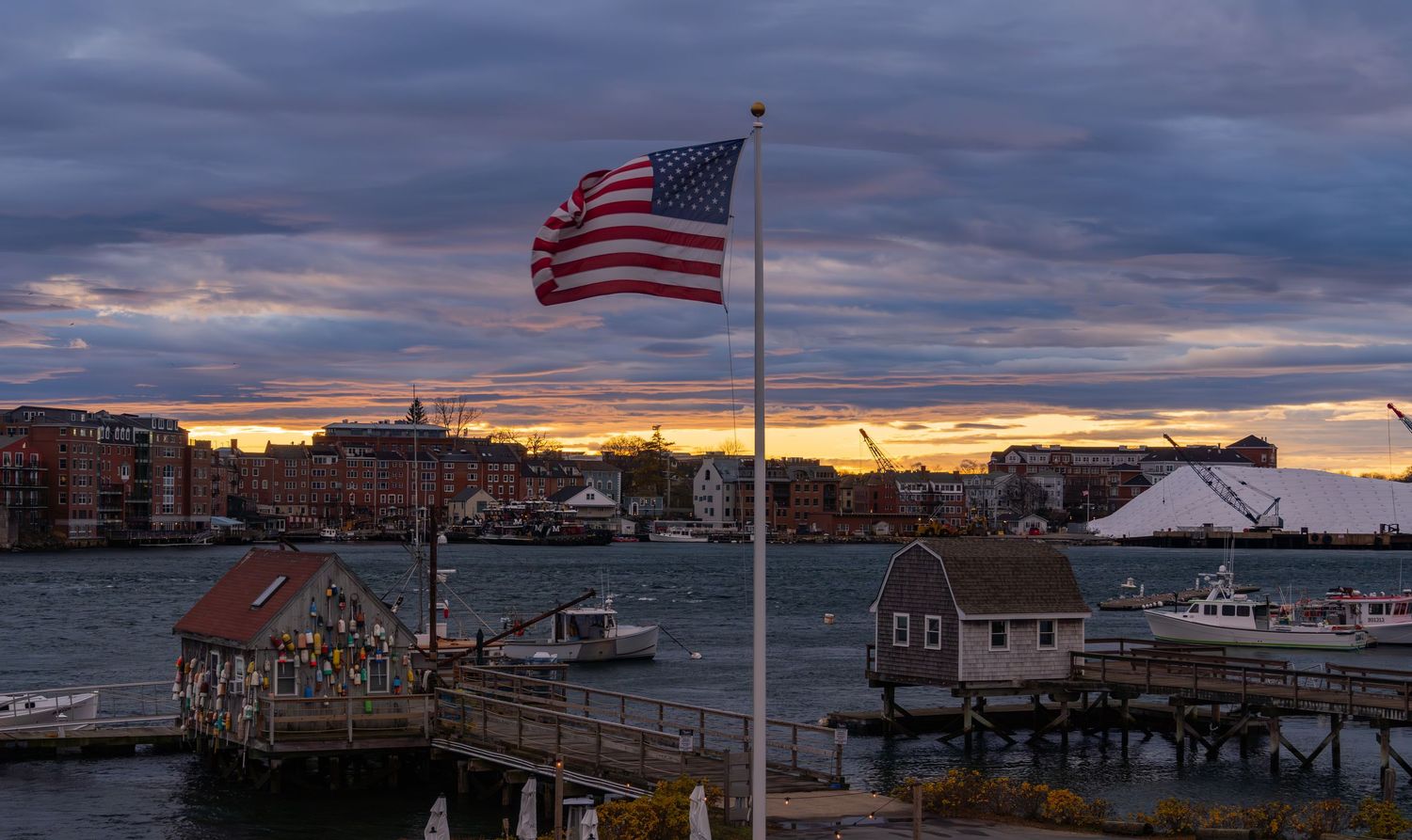 Panoramic view of Portsmouth town with historic buildings and American flags at sunset.