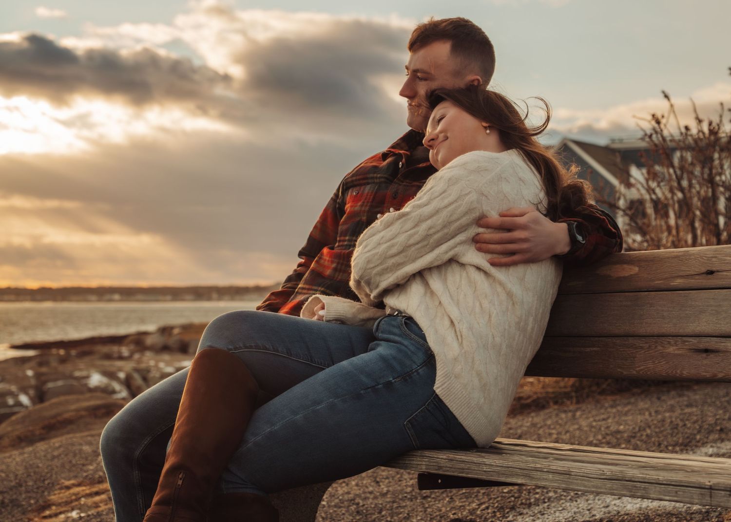 Couple relaxes on wooden deck during golden hour sunset.