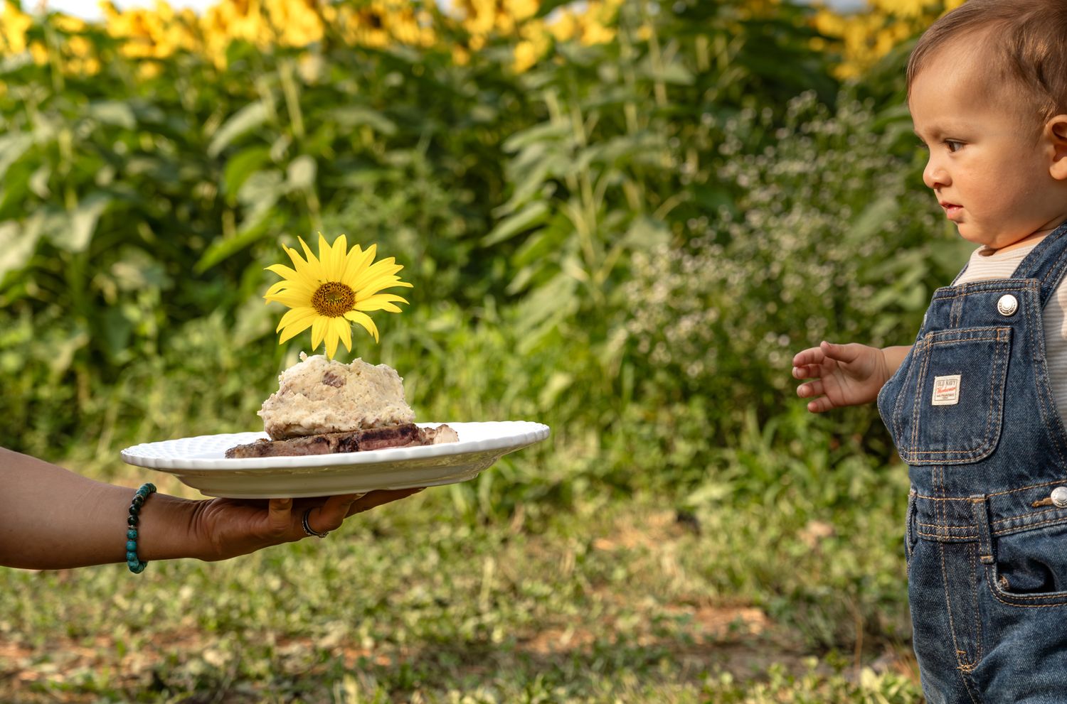 Child exploring in a sunflower garden with plates and gardening activities.
