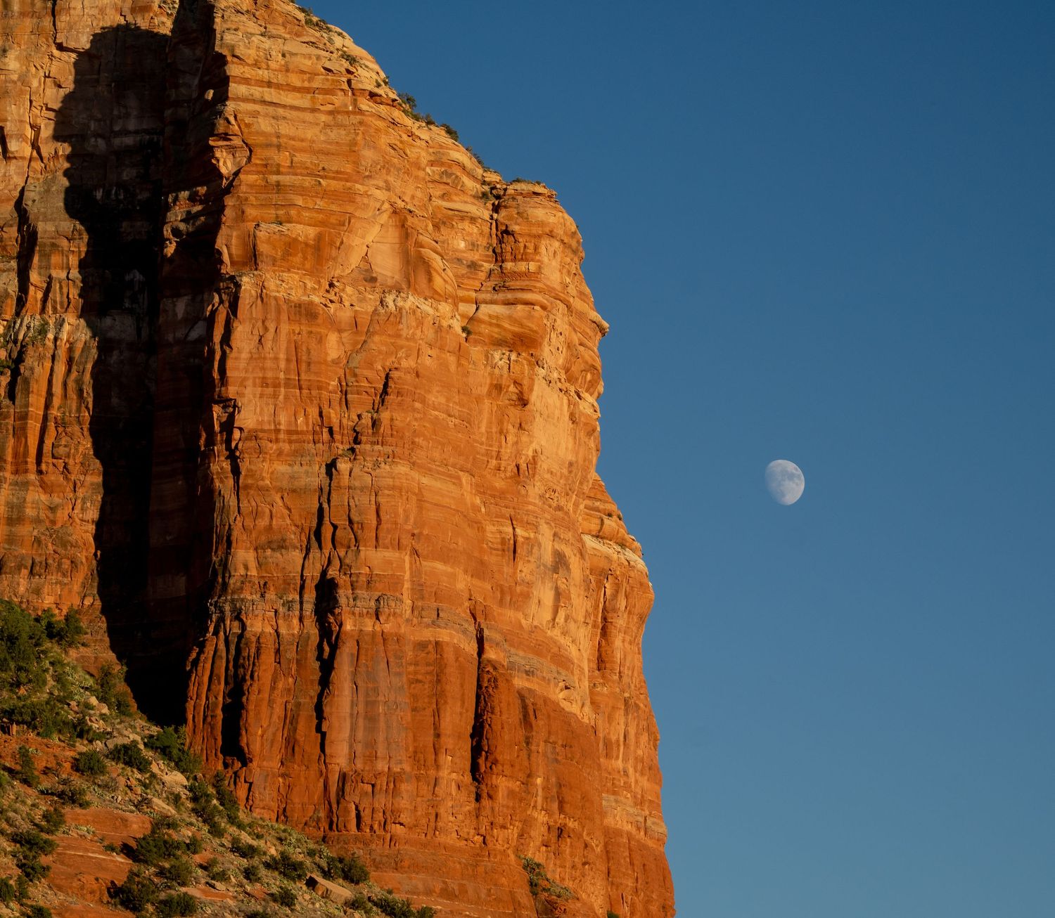 Moon rises over towering red sandstone cliffs in the desert southwest.
