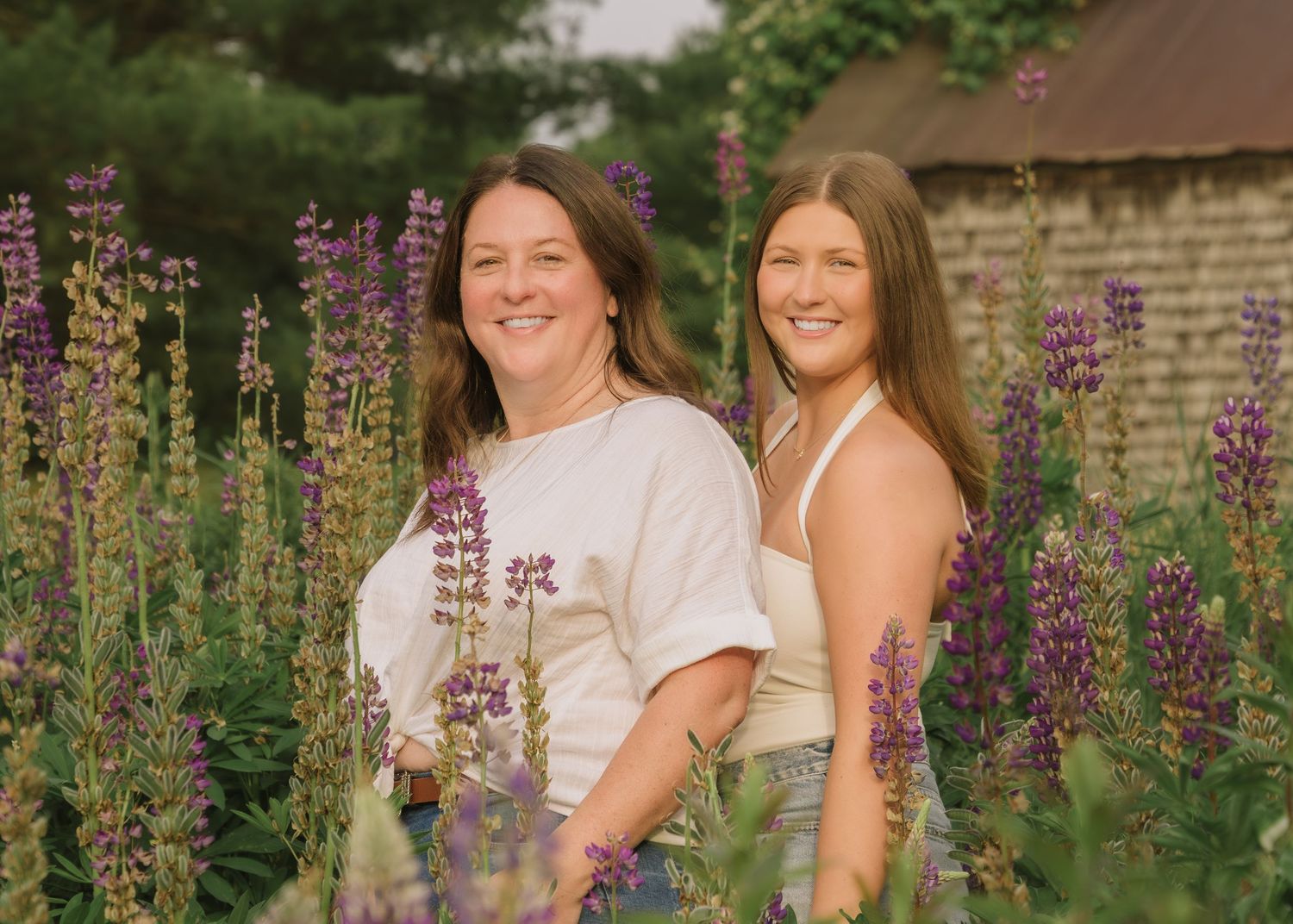 A group poses together in a garden with blooming purple lupine flowers in the background.