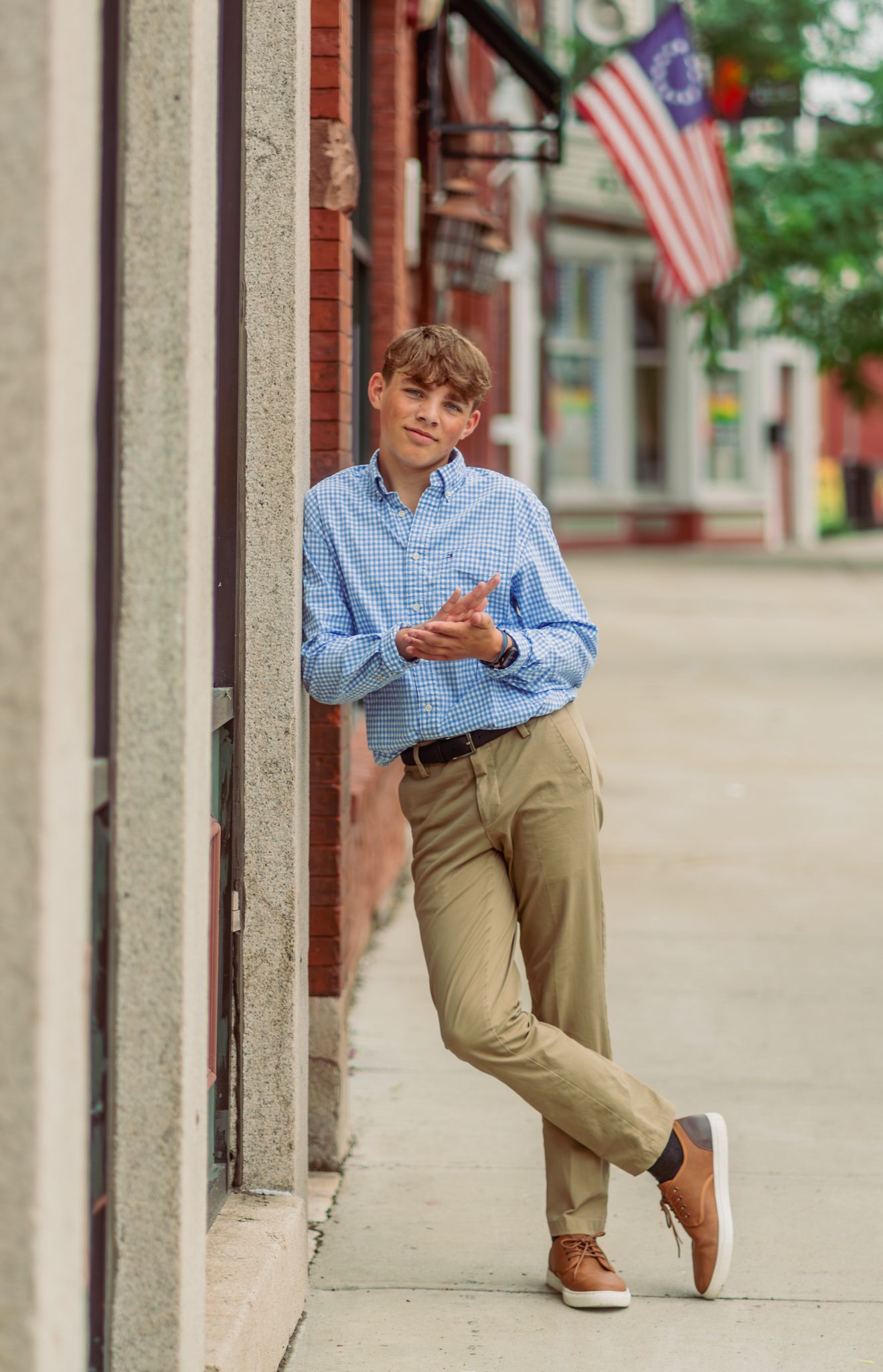 Casual portrait against brick wall with American flag in background showing preppy summer style.