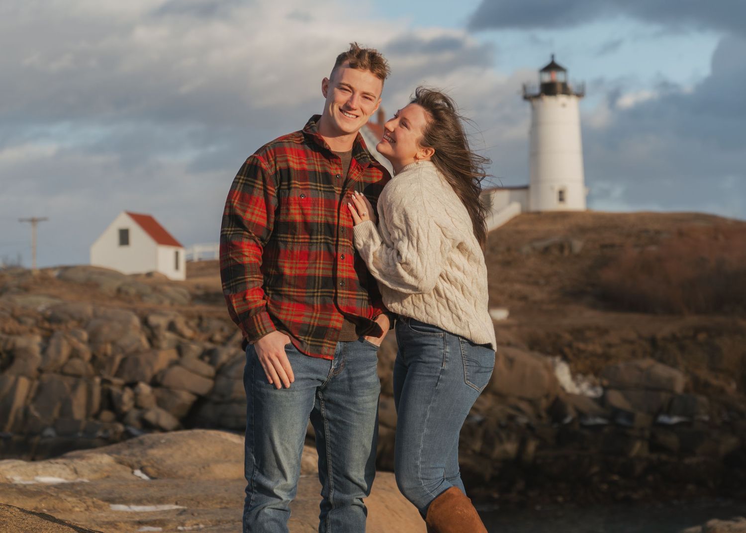 Lighthouse photography session on rocky coastal terrain at dusk.