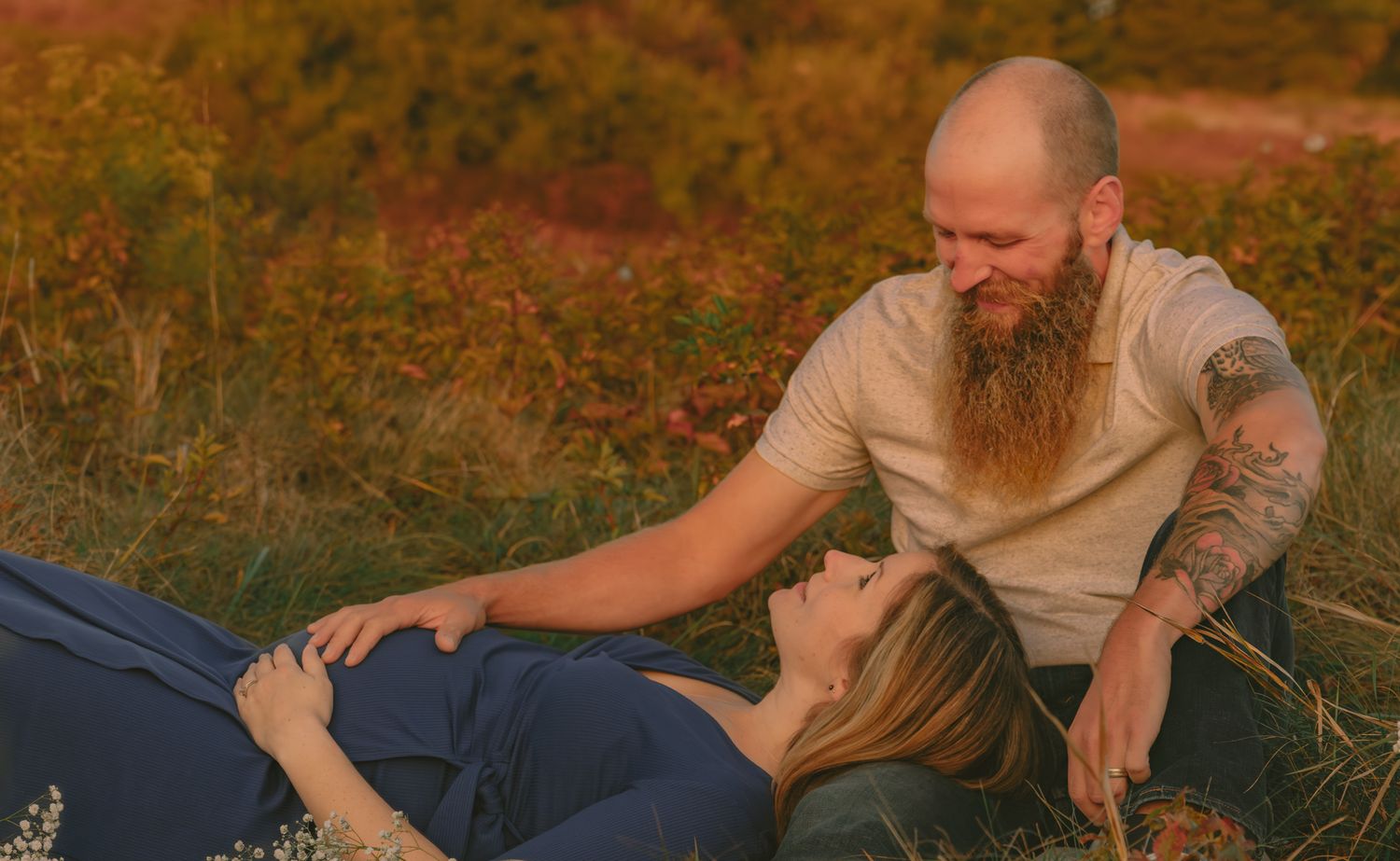 Intimate outdoor photoshoot in a rustic field at sunset with warm autumn lighting.