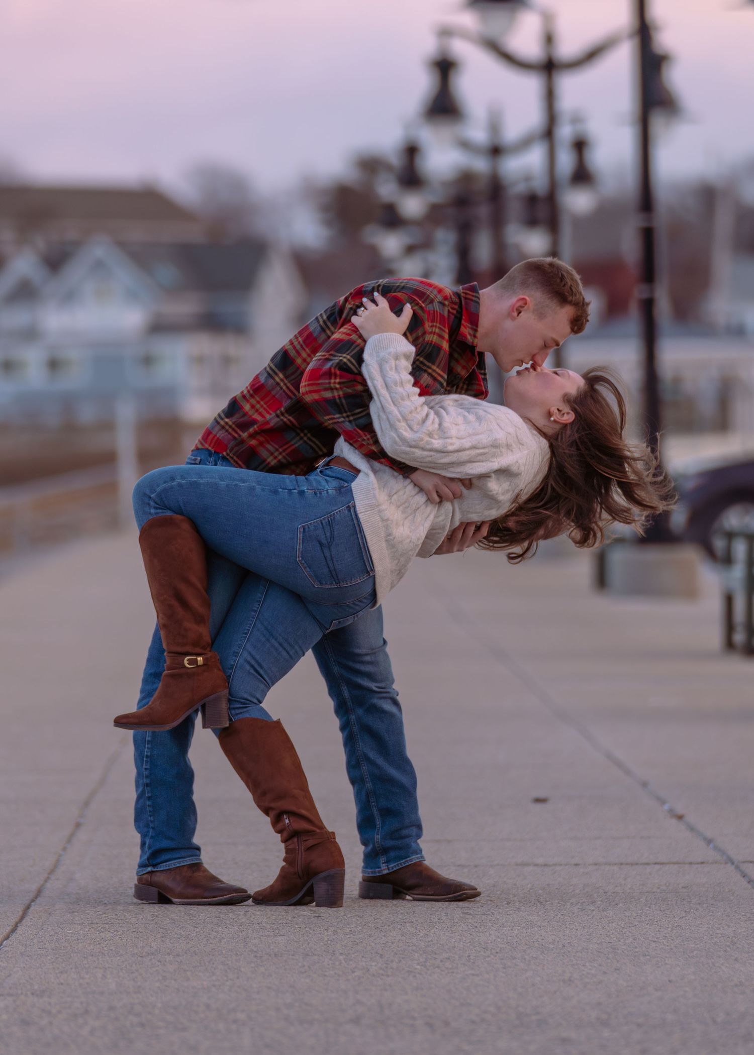 A romantic couple shares a playful dip kiss sequence on a concrete sidewalk.