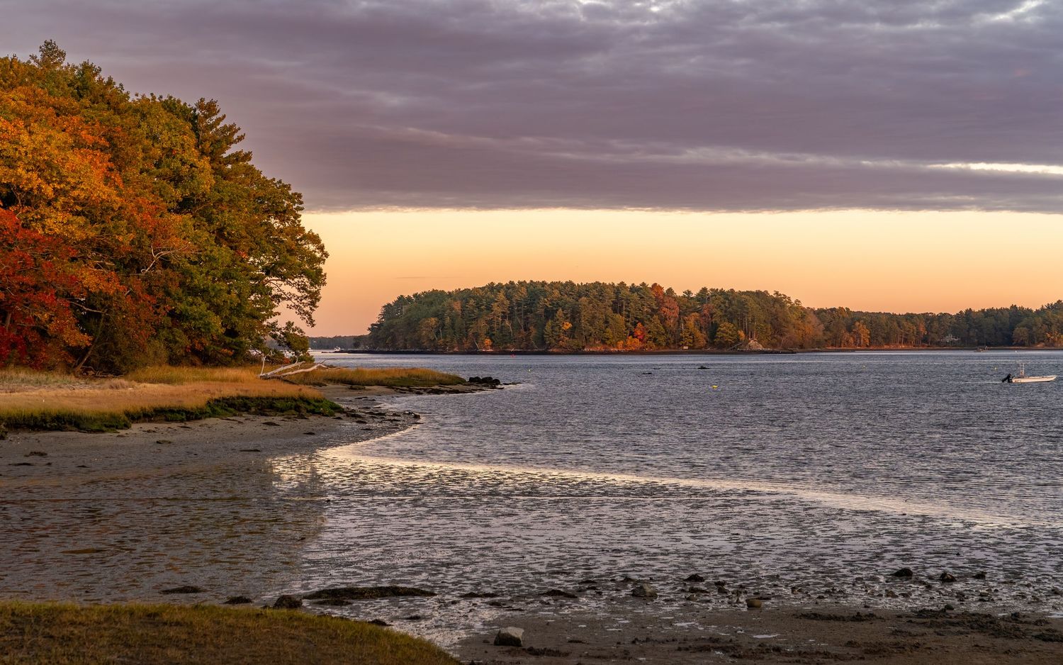 Panoramic view of a lake at sunset with dramatic clouds and fall colors along the shoreline.